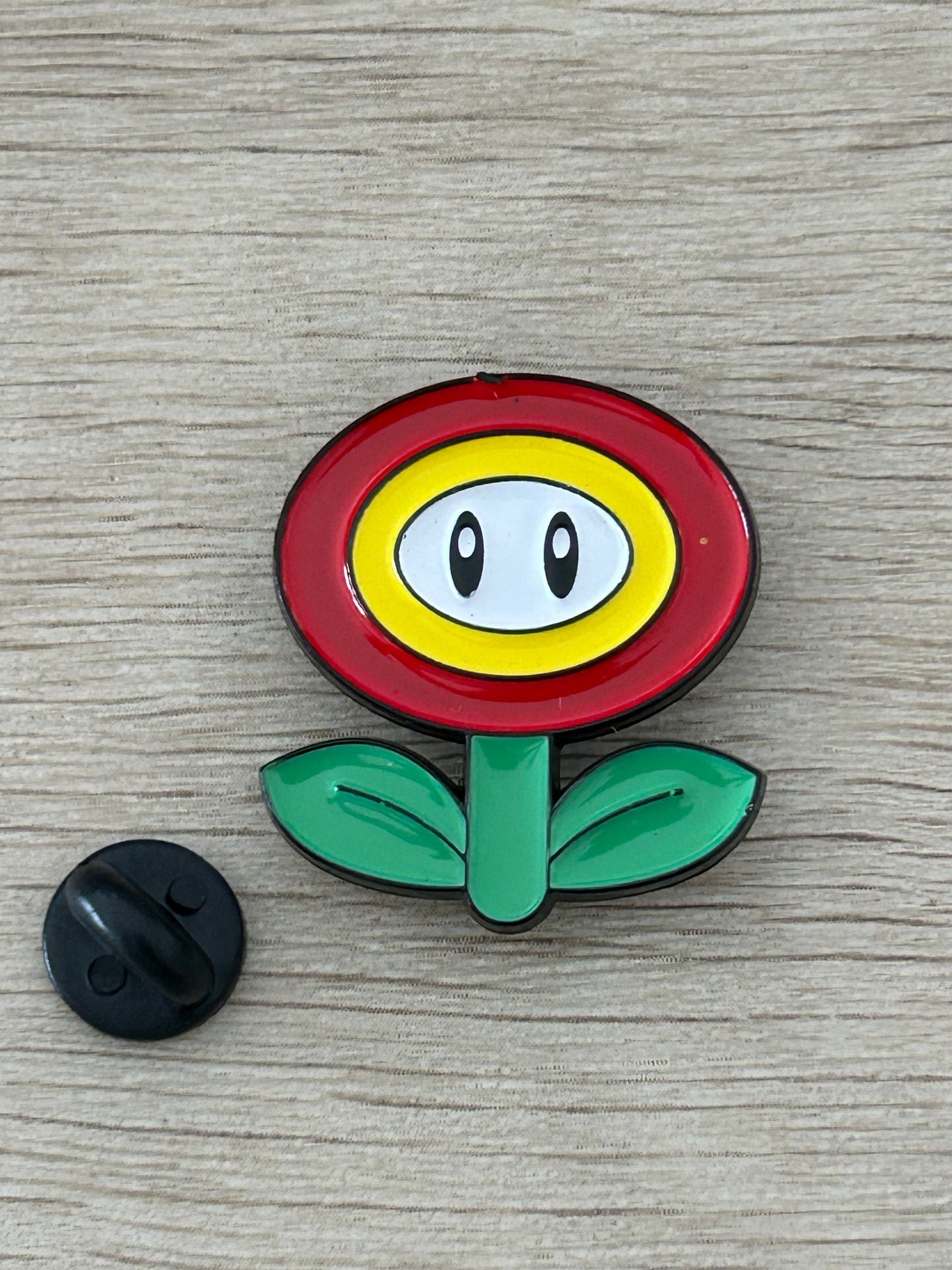 Épinglette fleur de feu Super Mario, face rouge et feuilles vertes, attache arrière noire
