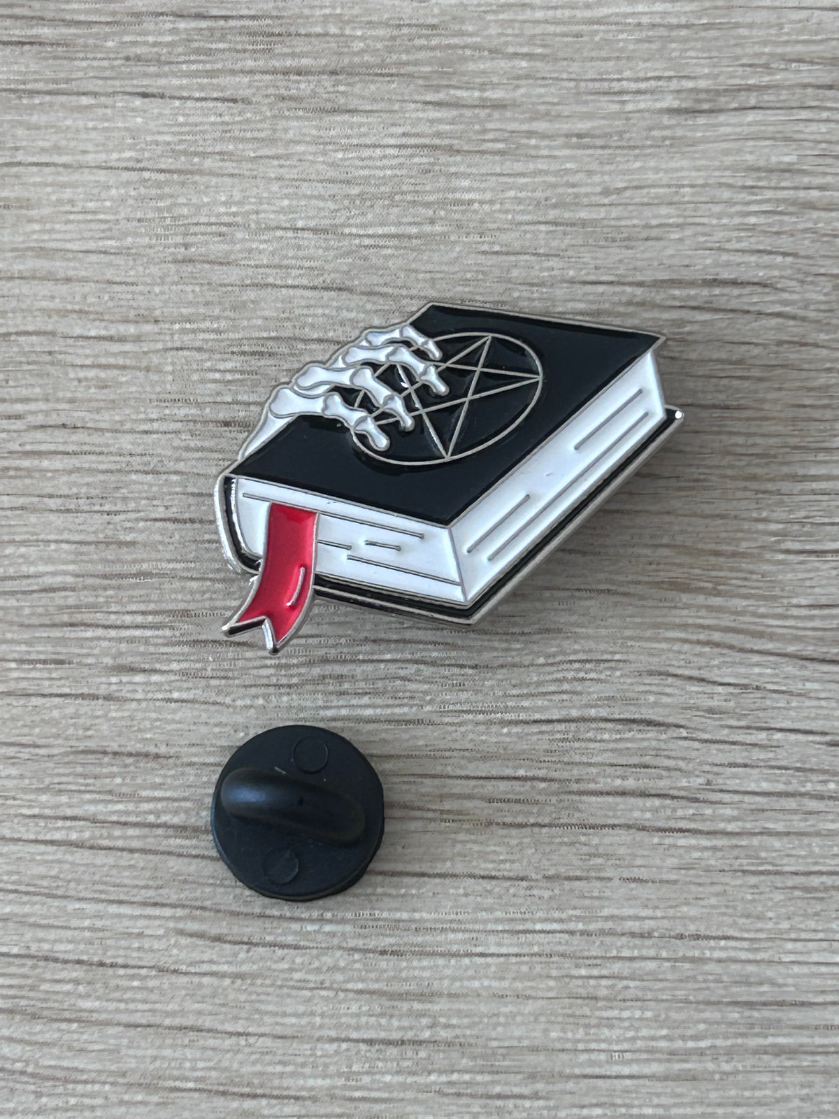 Épingle grimoire noire main squelettique argent, avec attache arrière ronde noire.