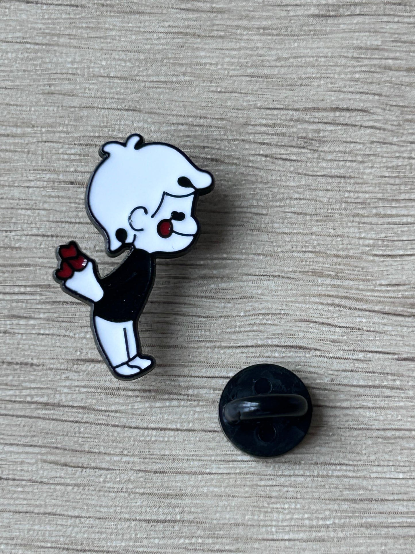 Pin's petit garçon cartoon noir et blanc tenant un bouquet de fleurs rouges