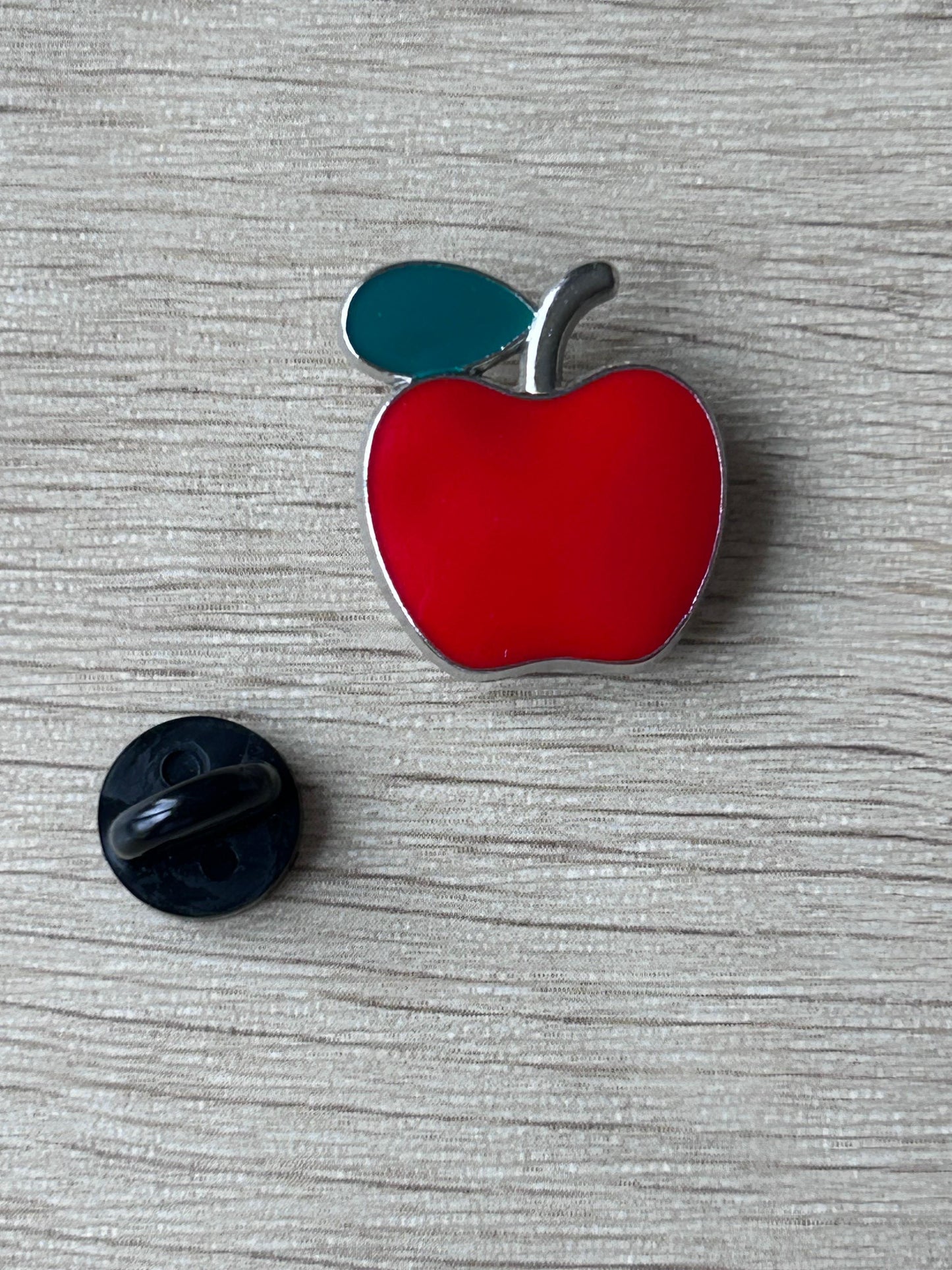 Broche en forme de pomme rouge avec feuille bleu-vert et attache arrière