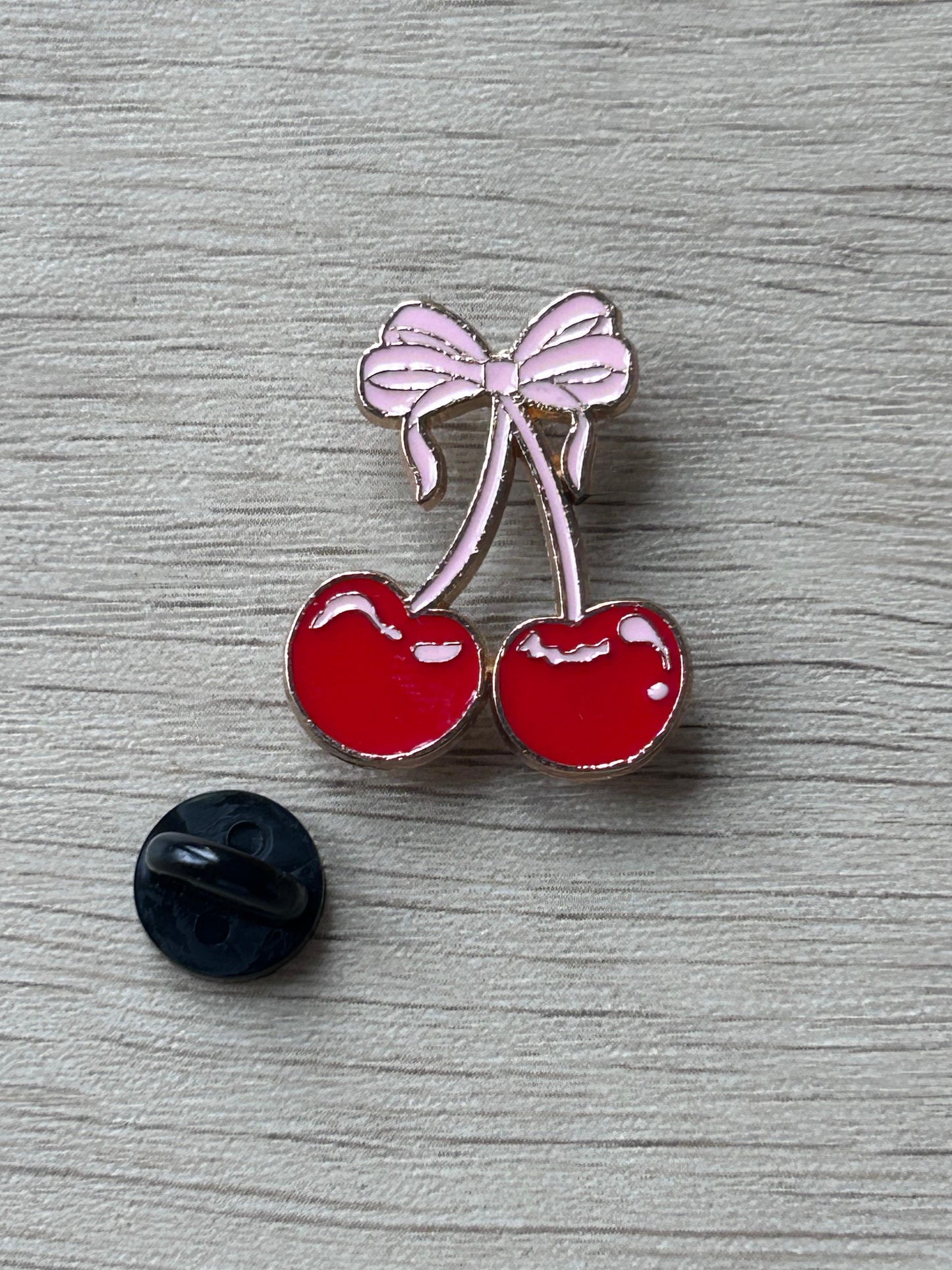 Pin en émail de cerises rouges avec nœud rose, vue de face