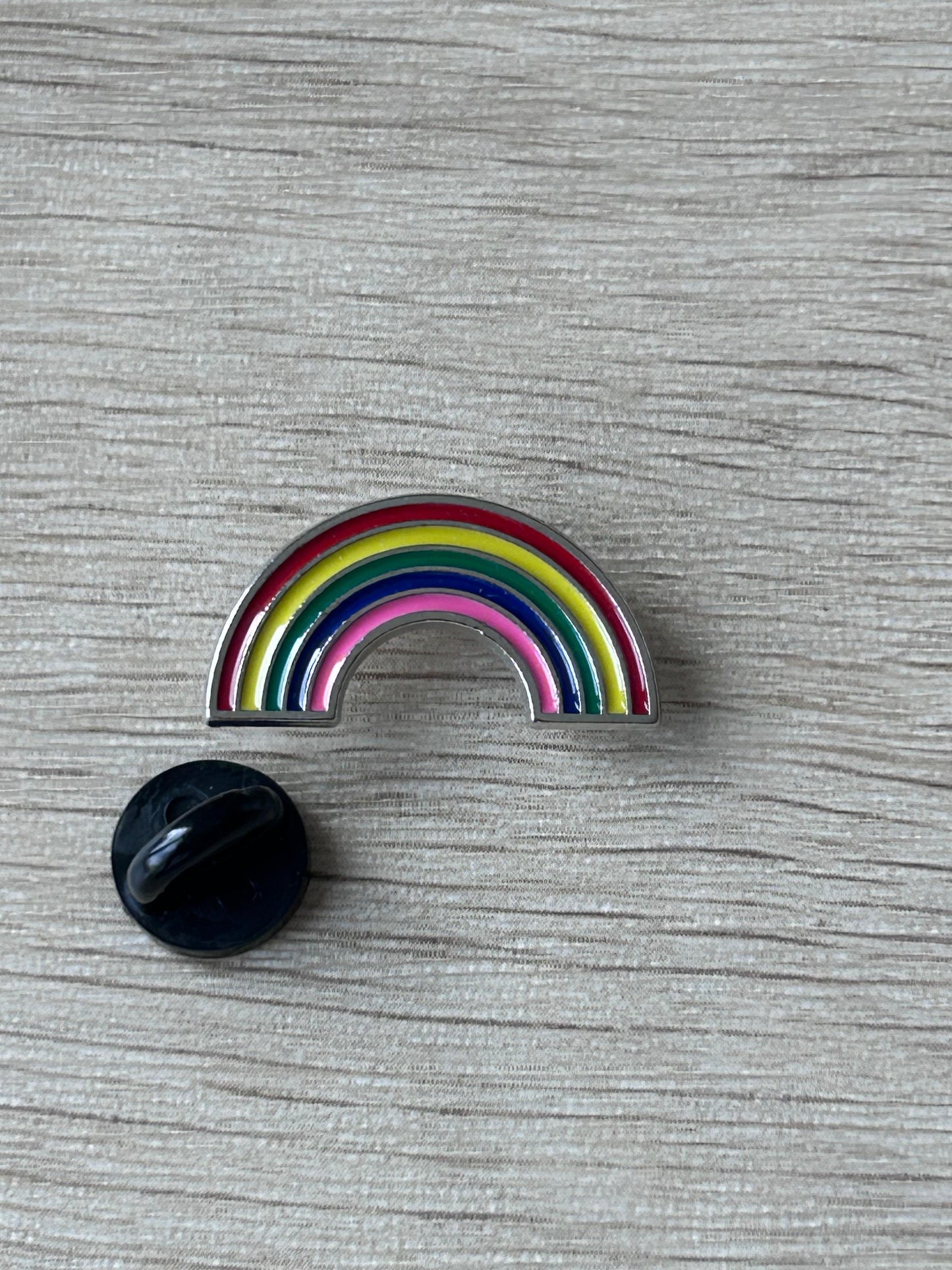 Épingle arc-en-ciel en forme d’arc, rayures multicolores, avec dos noir.