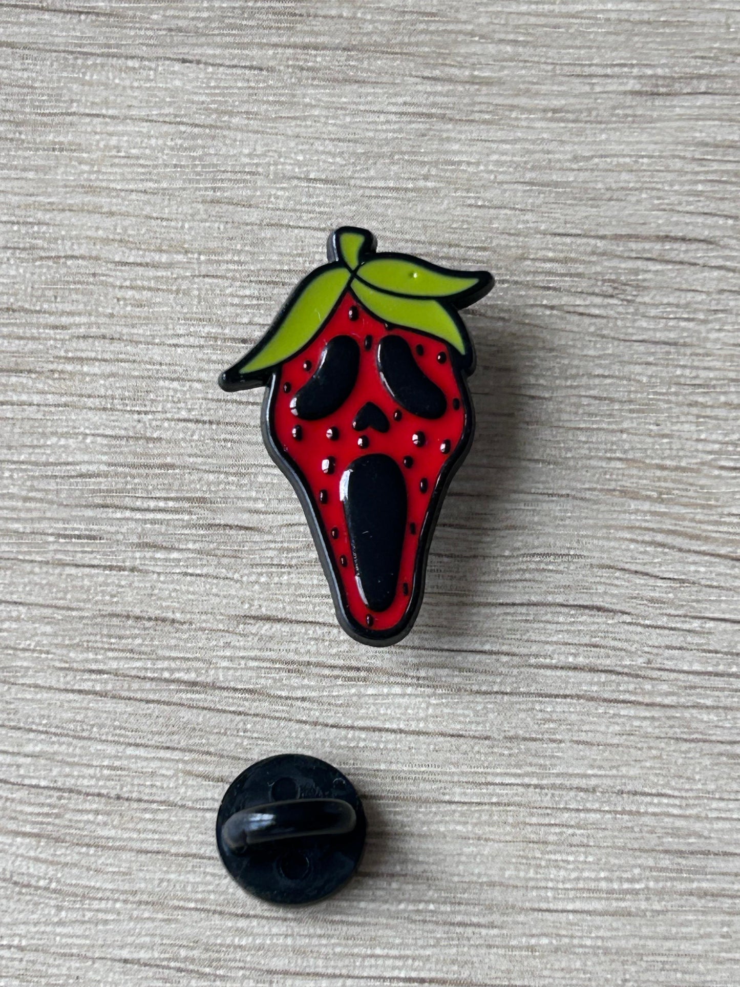 Épingle à dos rond noir sous la fraise rouge et feuilles vertes