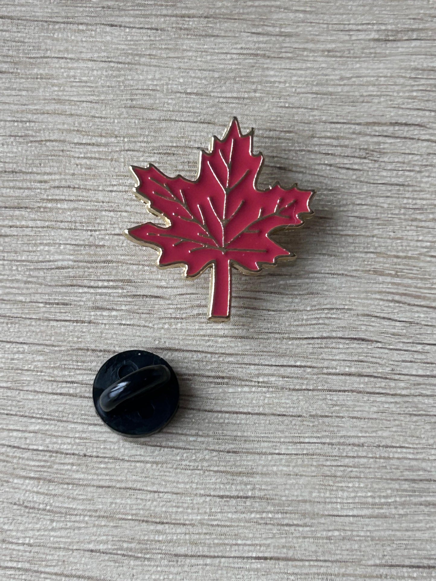 Broche feuille d’érable rouge émaillée avec contour argenté et tige centrale.