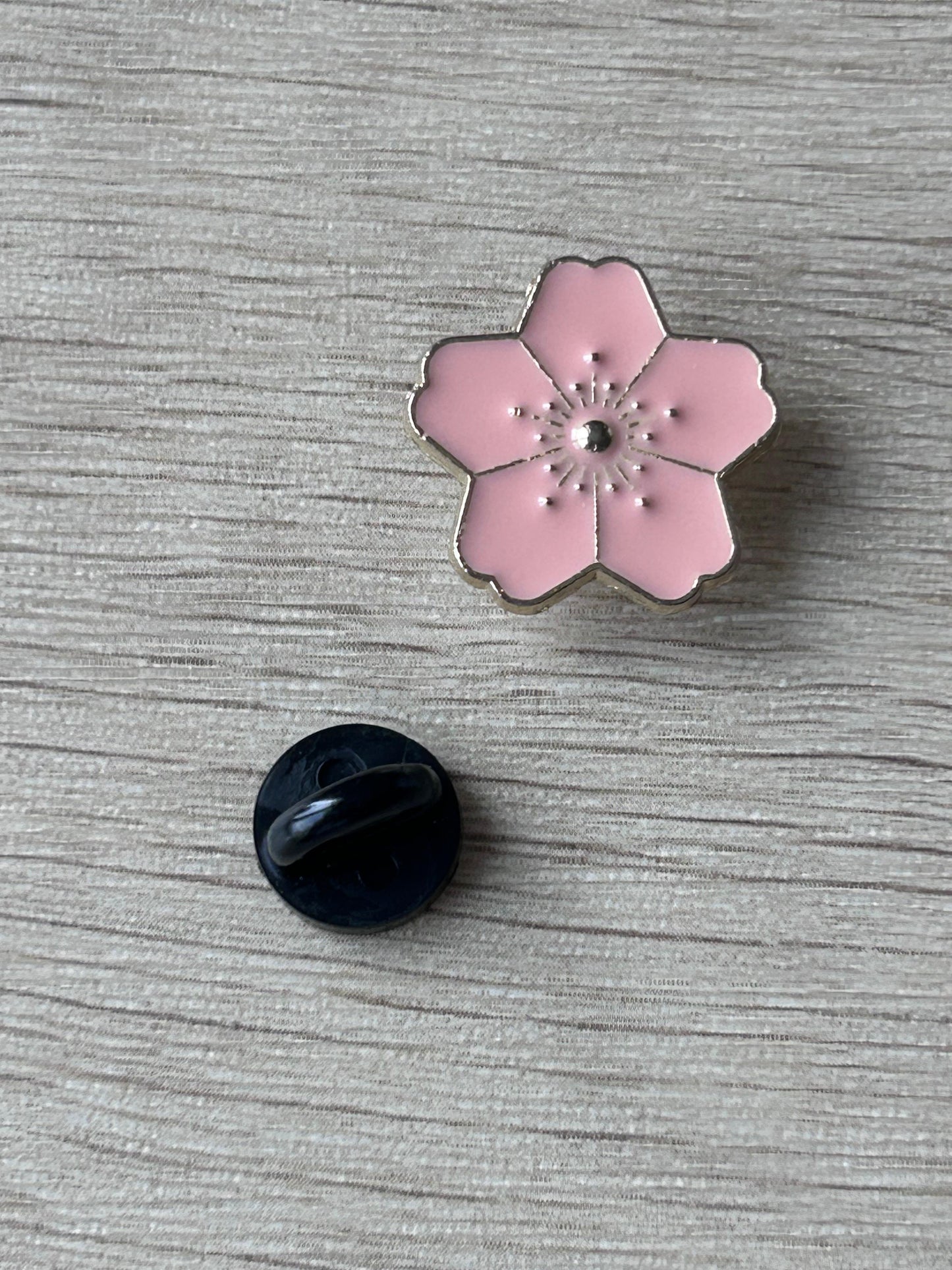 Broche fleur de cerisier rose avec bord noir et centre, dos noir rond visible