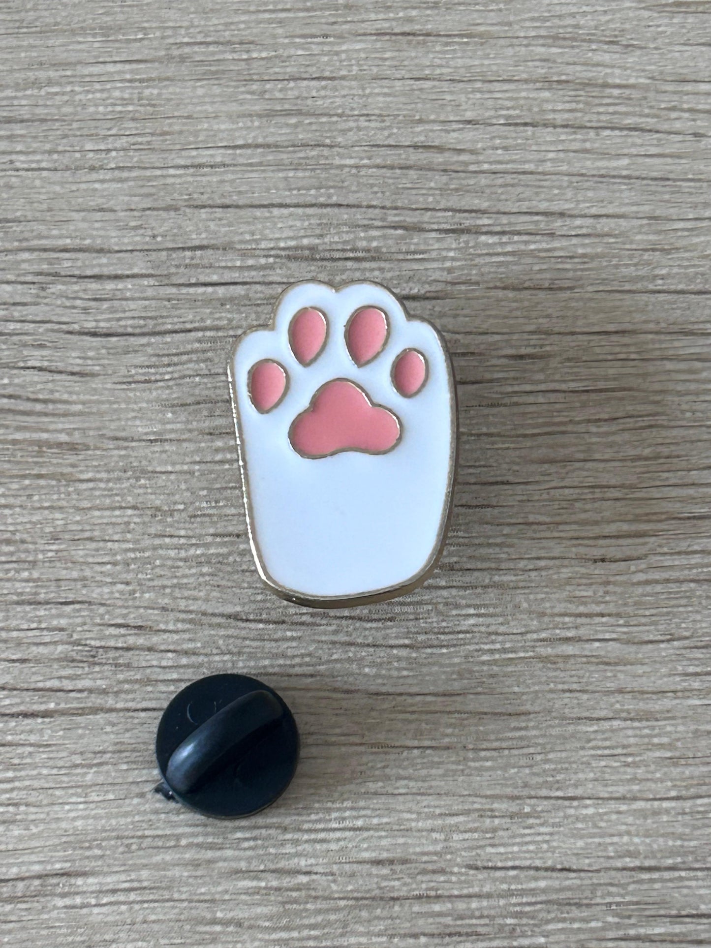 Broche patte de chat émaillée bleu clair avec coussinets roses, dos noir visible