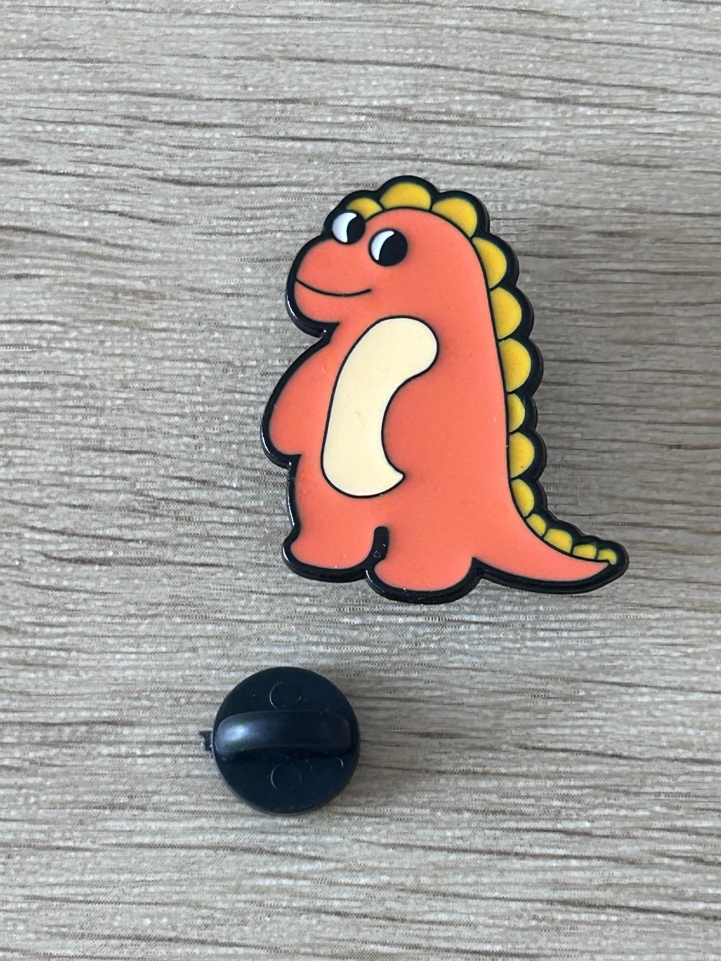 Épingle dinosaure orange kawaii avec attache noire ronde