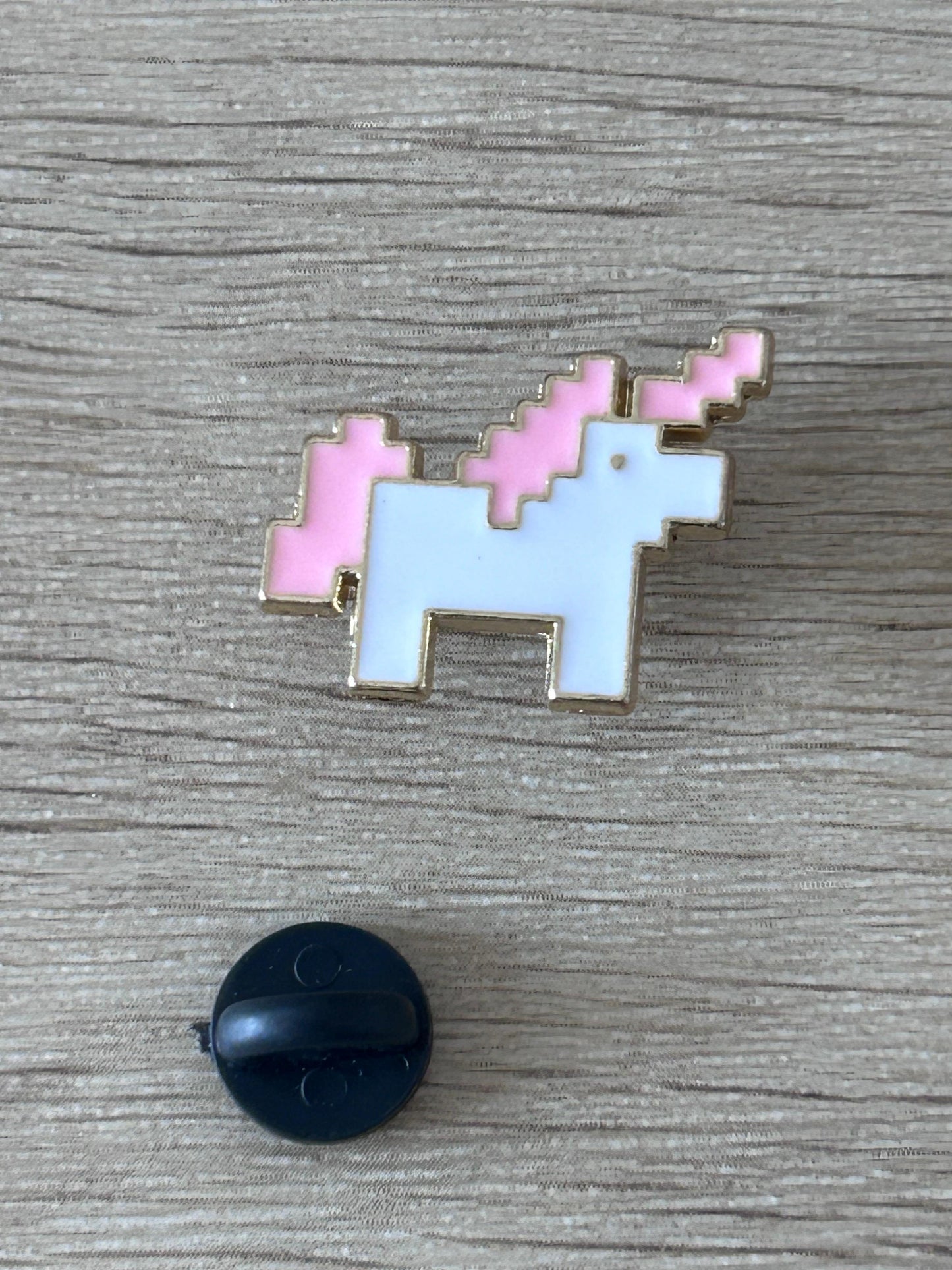 Pin en forme de licorne pixel art, corps blanc, crinière rose, contour doré