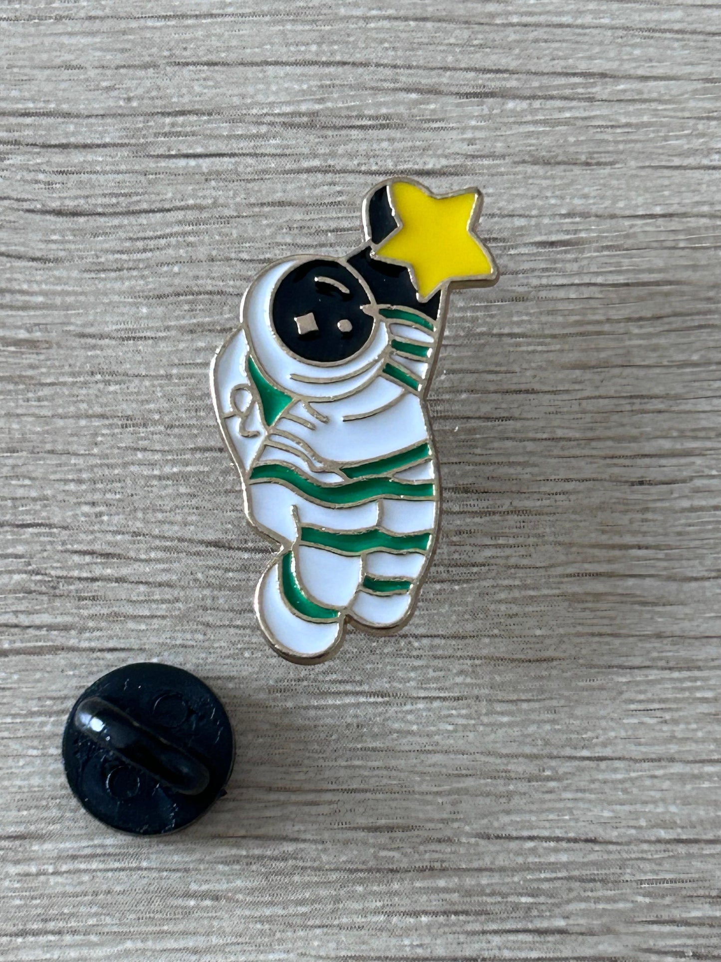 Pin en émail astronaute et étoile jaune, avec agrafe noire visible
