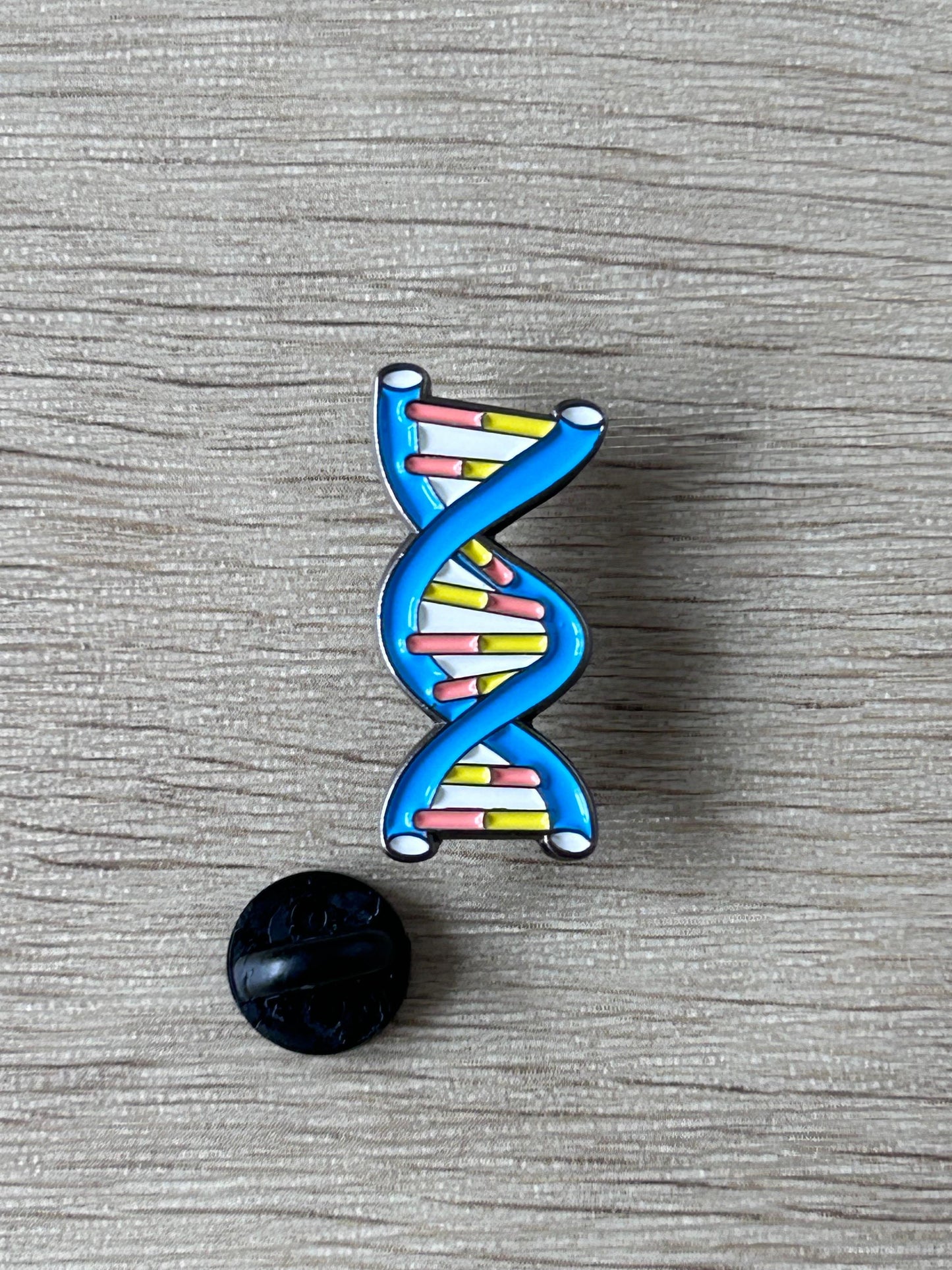 Pin's double hélice ADN bleu avec attache noire au dos et barrettes multicolores