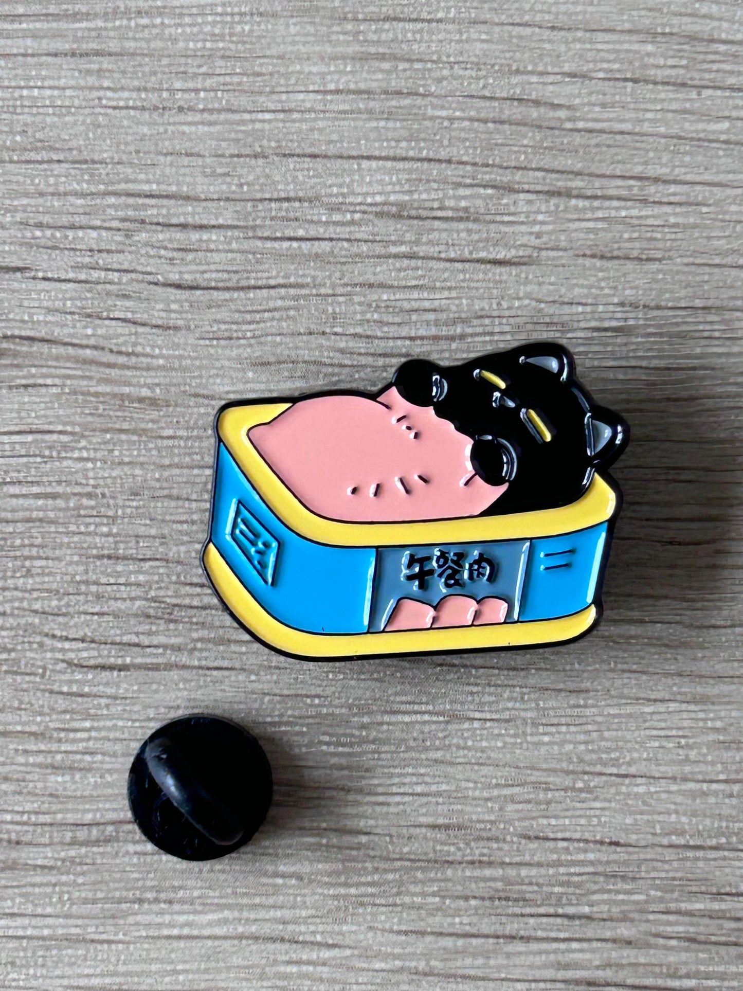 Pin émail chat noir dans boîte bleue bord jaune, vue rapprochée