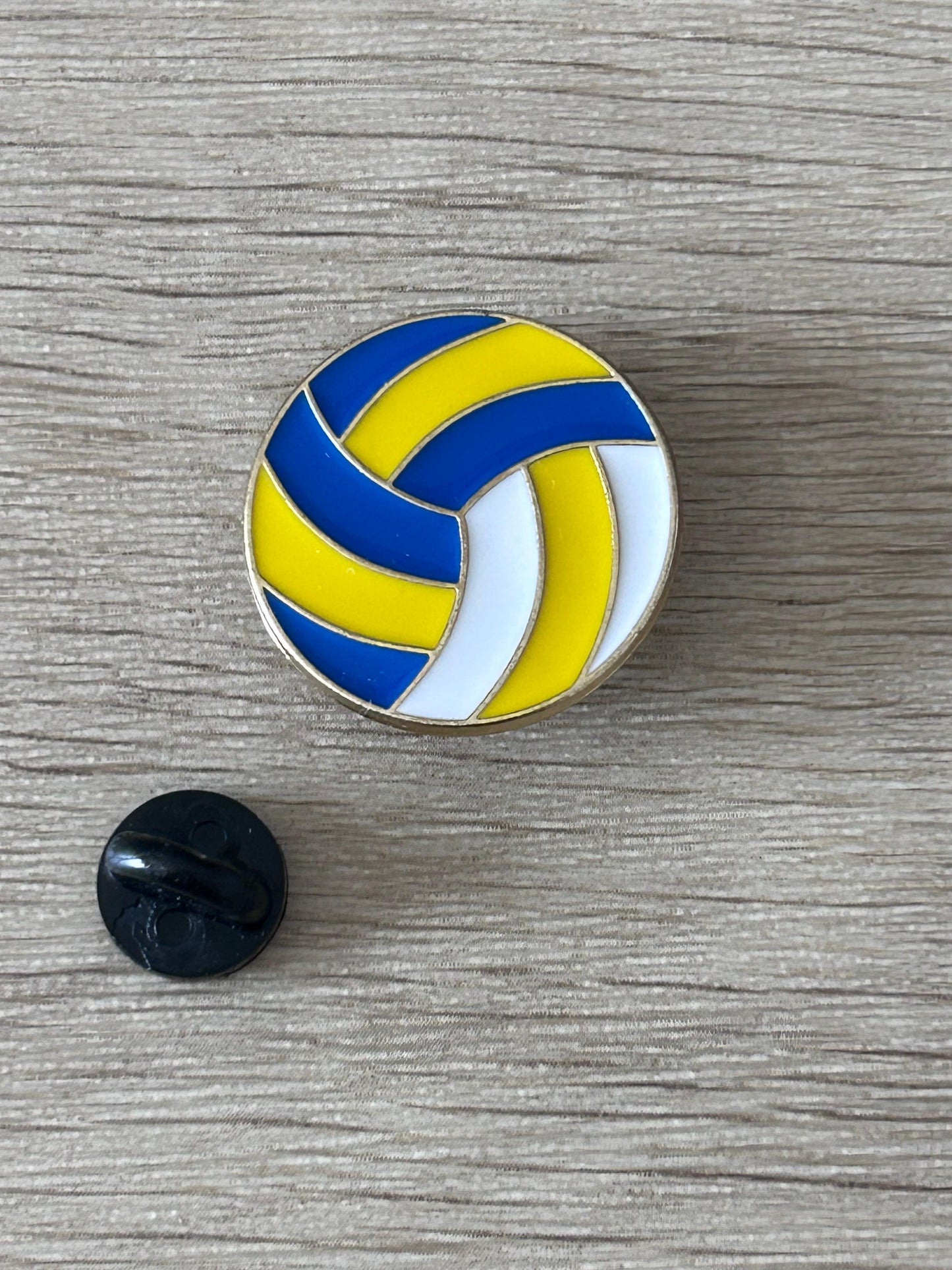 Épinglette ballon de volley-ball bleu et jaune avec attache noire à l’arrière.