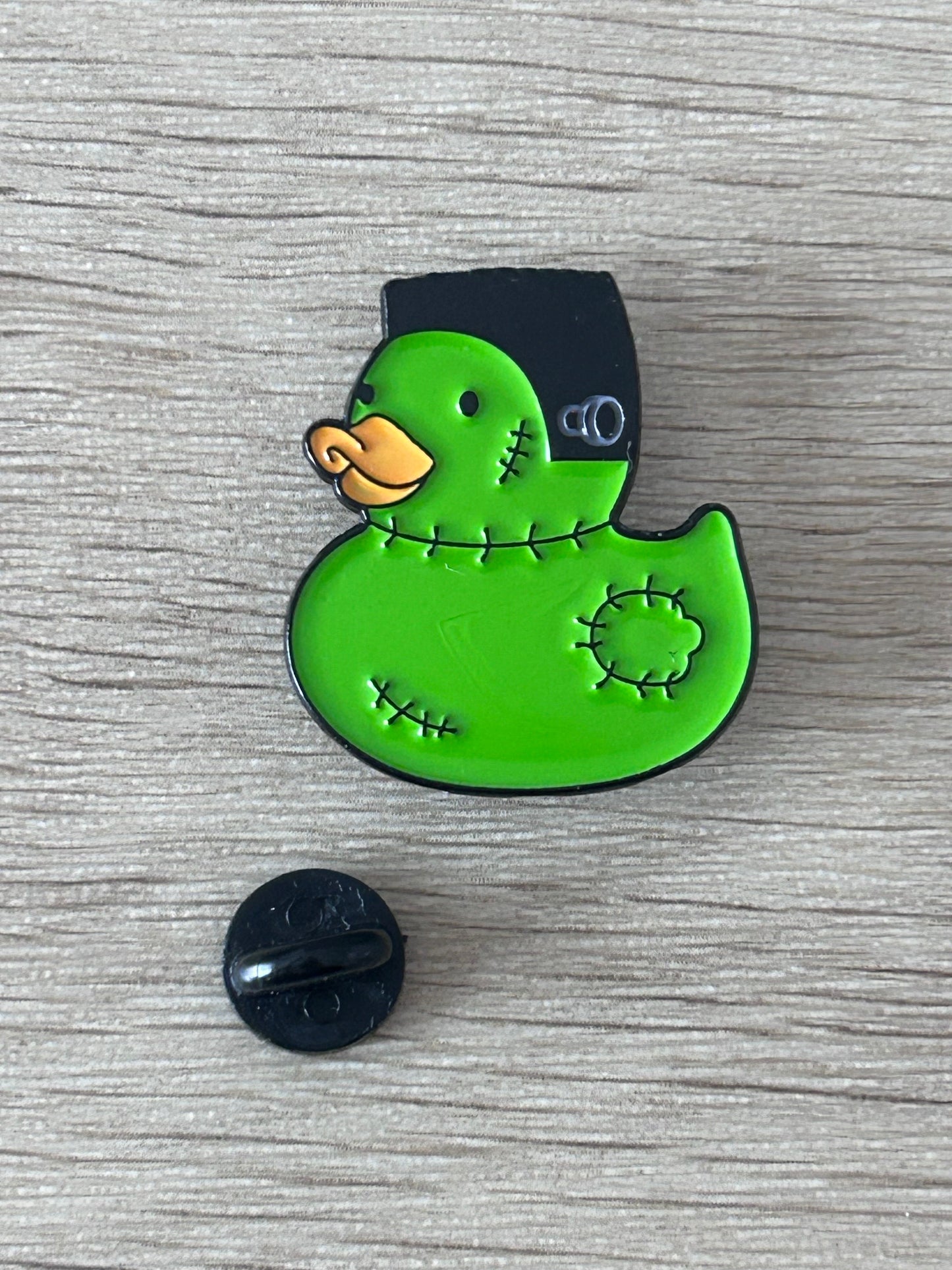 Épingle canard Frankenstein verte avec dos noir, épingle papillon noire à côté