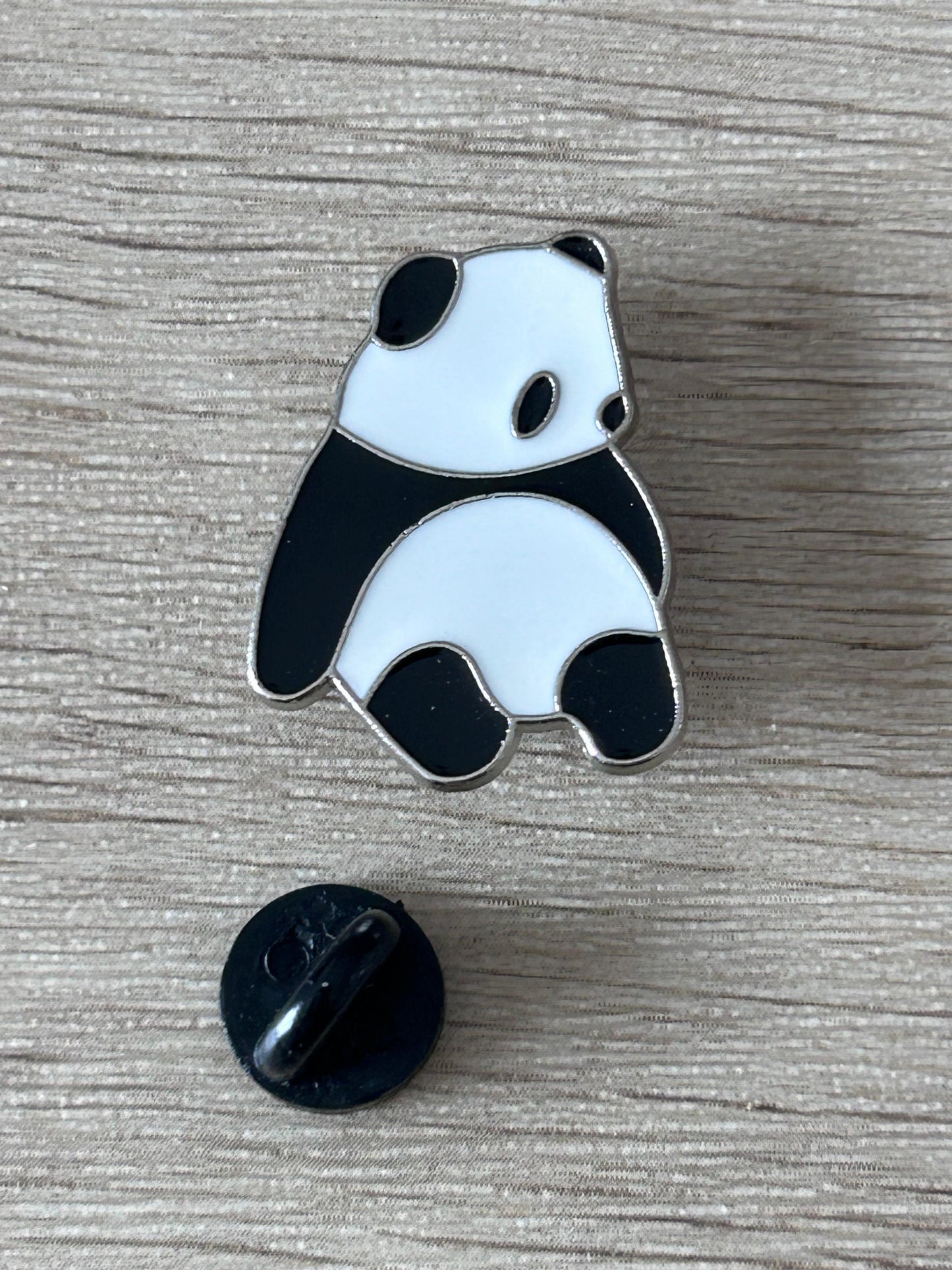 Pin's panda assis émaillé noir et blanc, attache arrière noire visible.