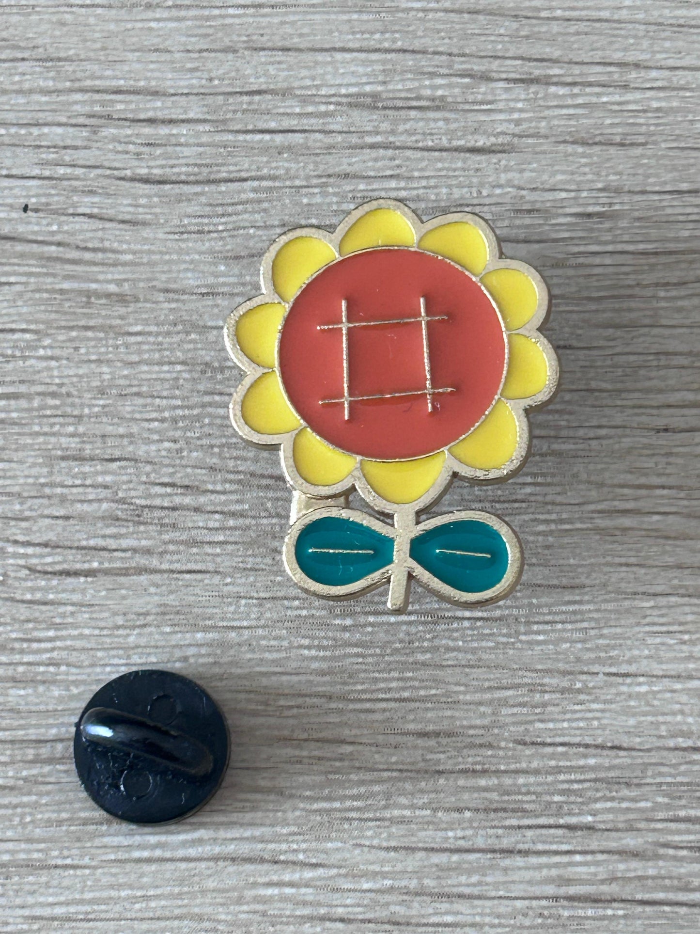 Broche pin tournesol à cœur rouge et pétales jaunes, base verte.