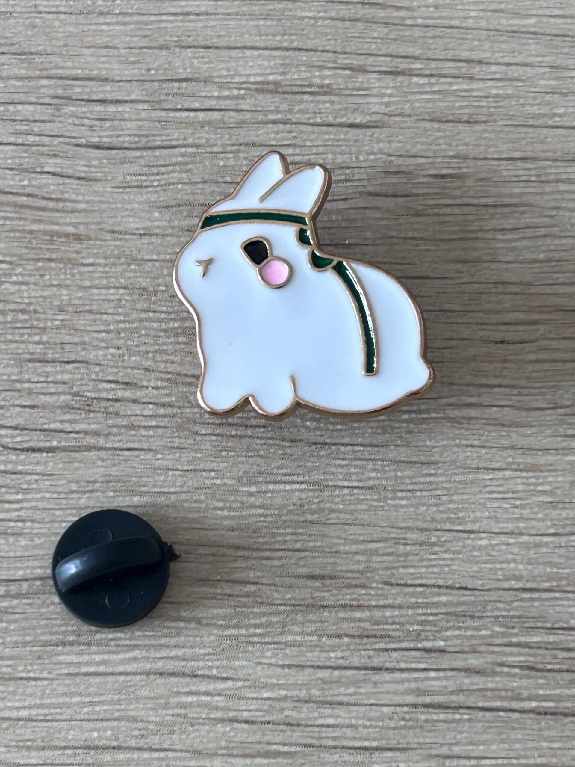 Broche lapin émaillée blanc, bandeau vert, nez rose; attache arrière noire visible