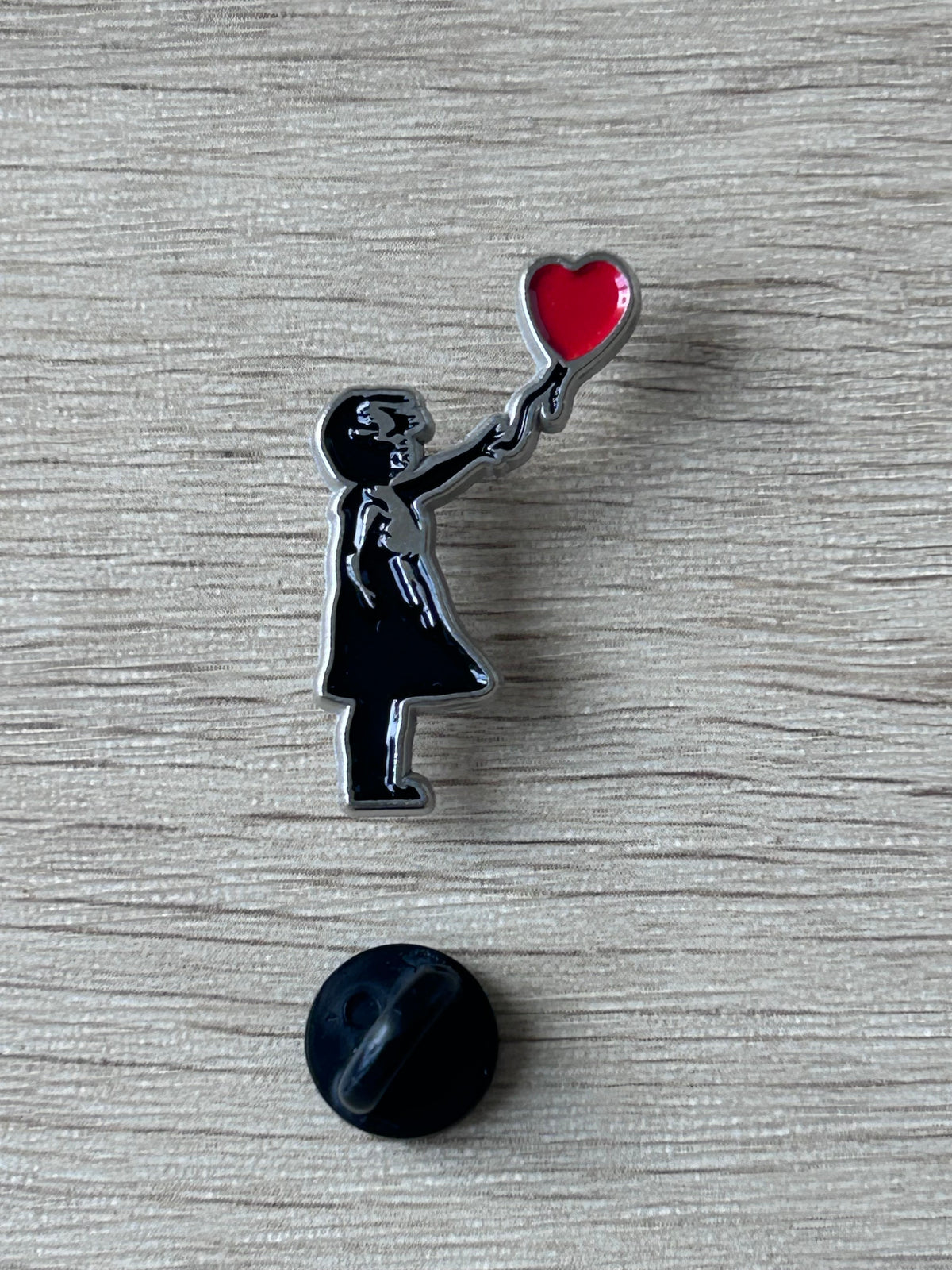 Épingle décorative avec petite fille tenant un ballon en forme de cœur rouge et son fermoir noir