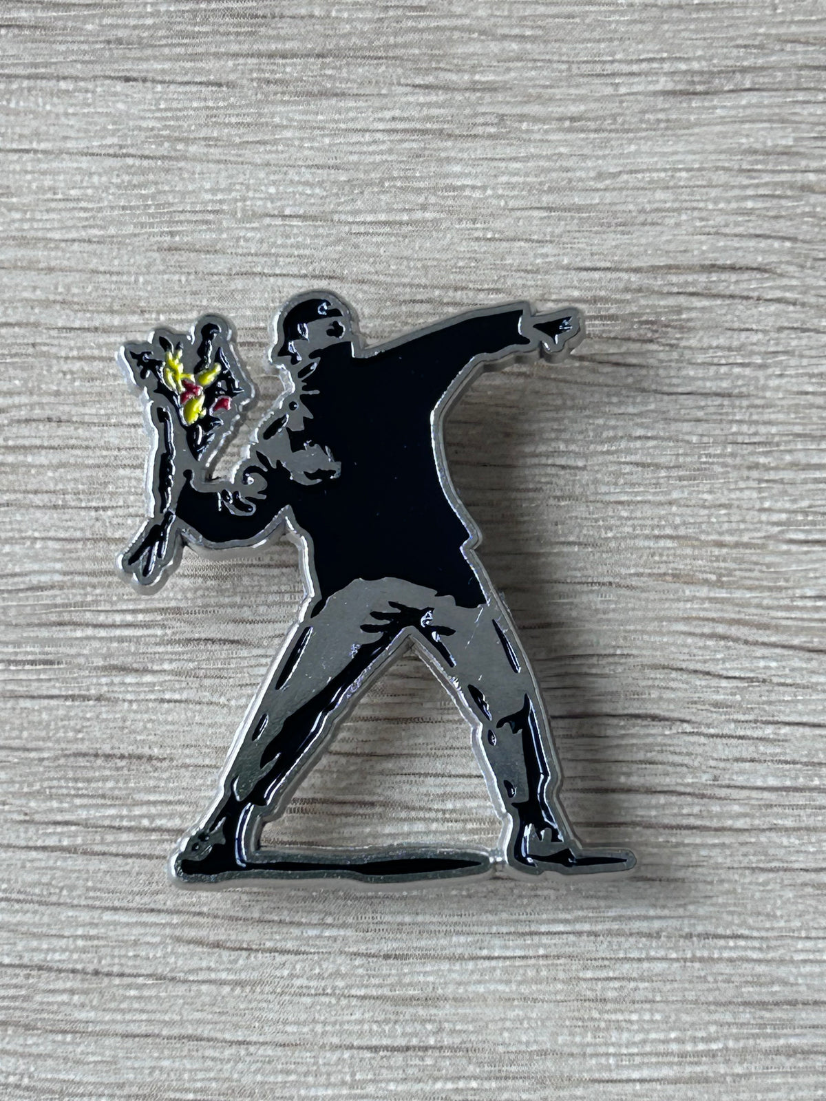 Broche lanceur de fleurs, silhouette noire avec fleur jaune/rouge.