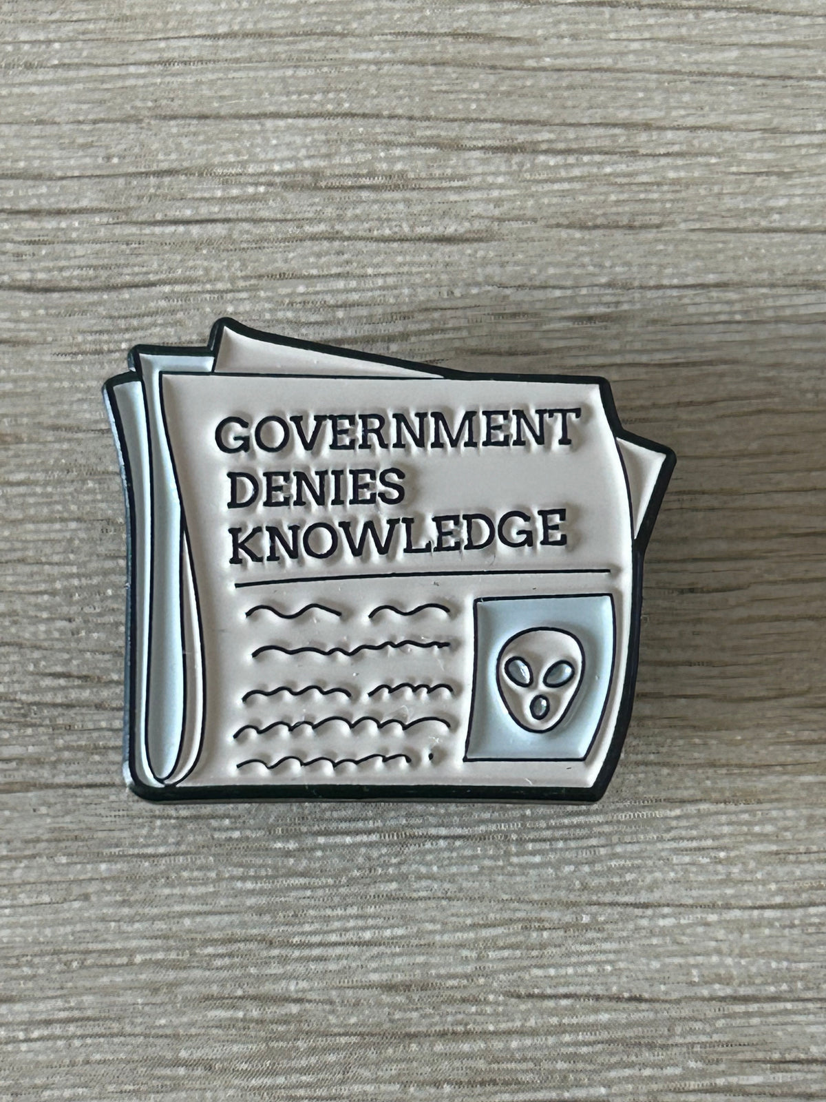 Vue rapprochée du pin's journal Government denies knowledge et de son alien