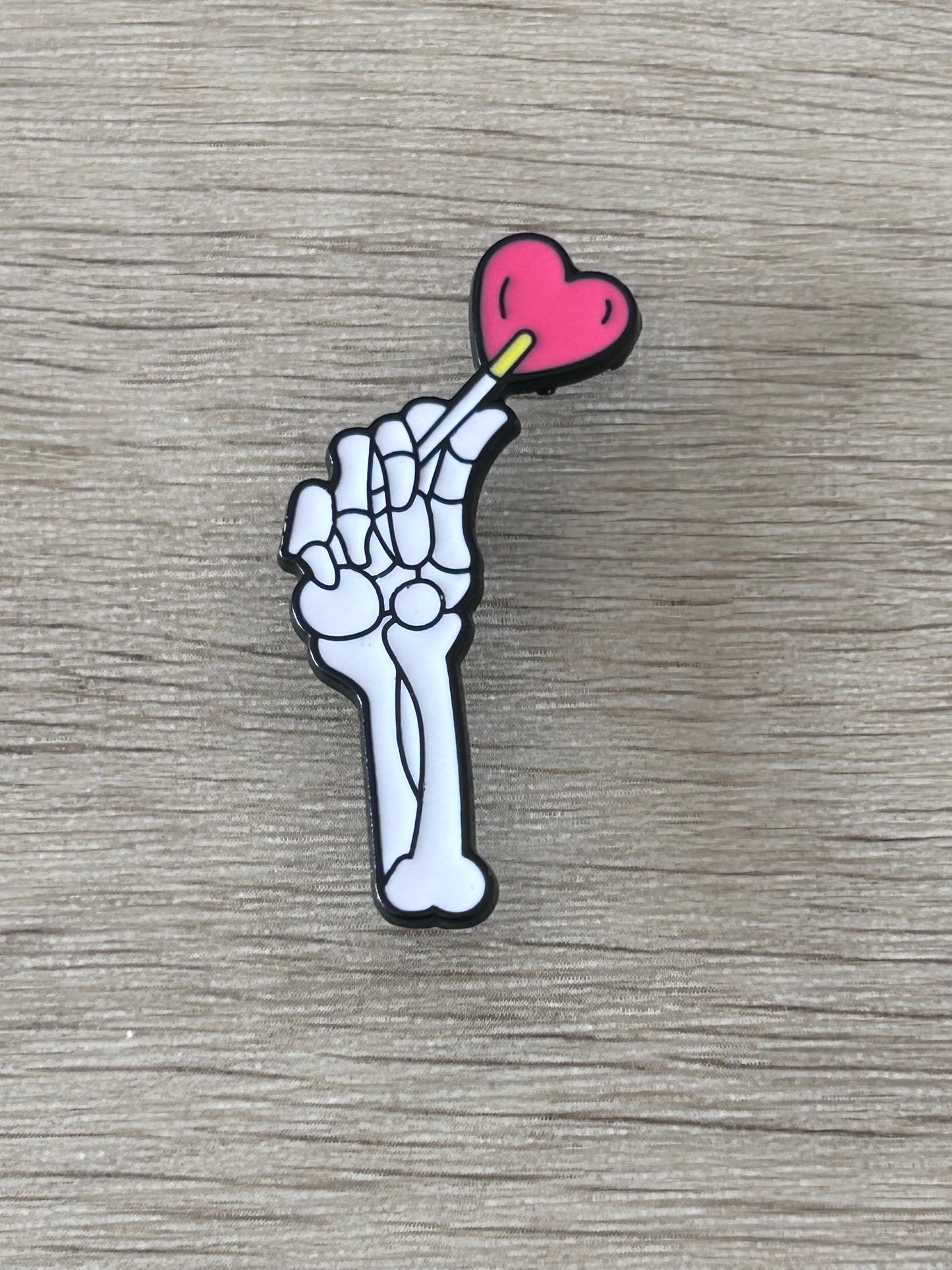 Pin en forme de main de squelette avec cœur rose et détail jaune