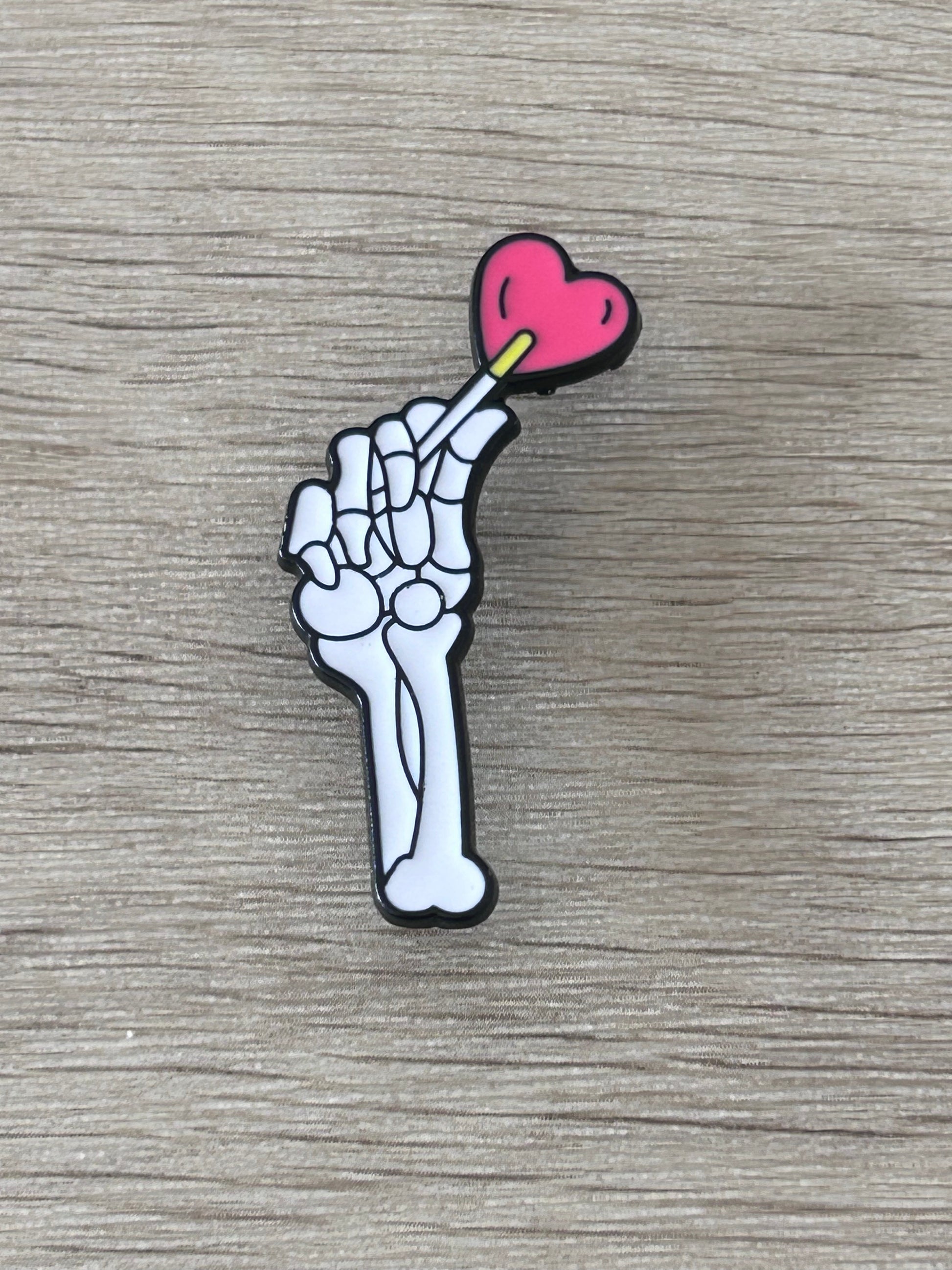 Pin en forme de main de squelette avec cœur rose et détail jaune