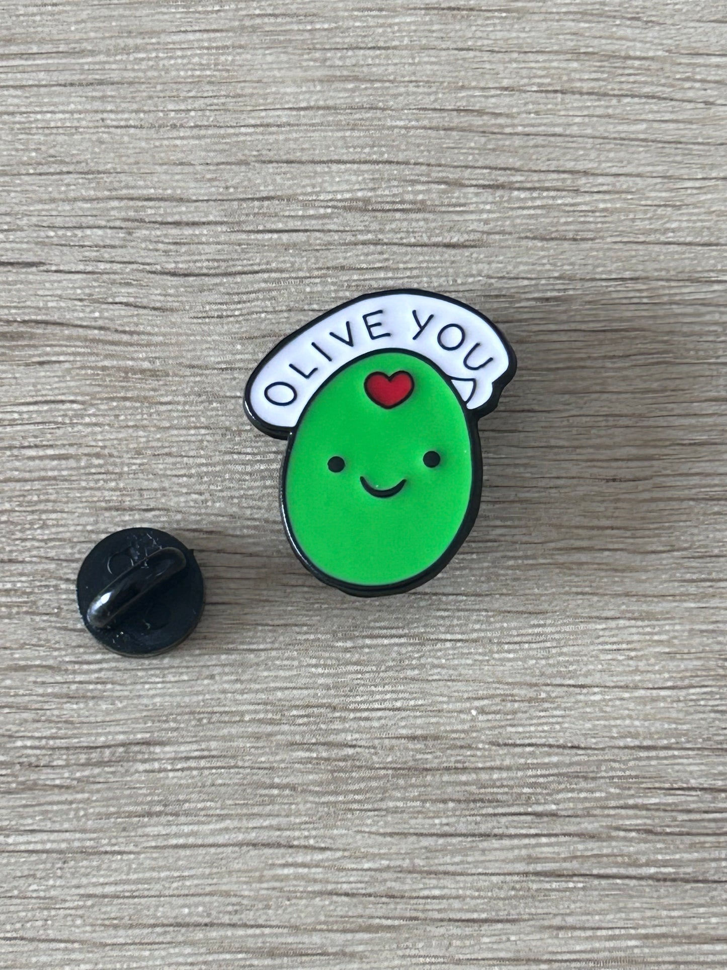Épingle olive verte « OLIVE YOU » avec visage; attache arrière noire.