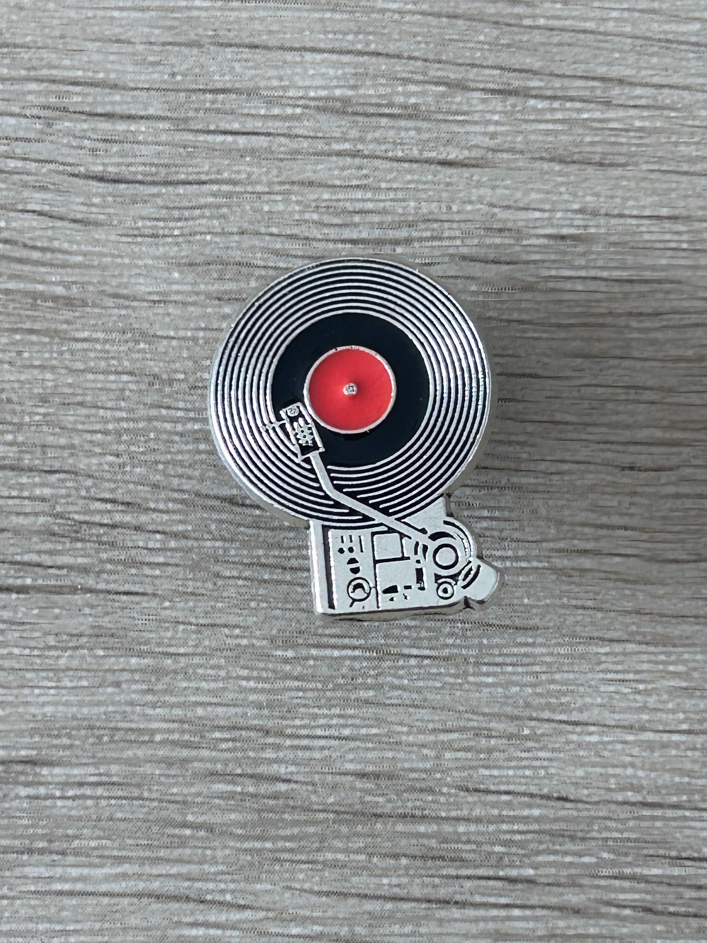 Épingle platine vinyle avec disque noir strié, centre rouge et bras de lecture