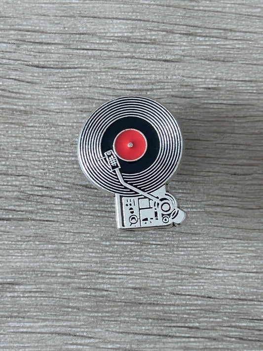 Épingle platine vinyle avec disque noir strié, centre rouge et bras de lecture
