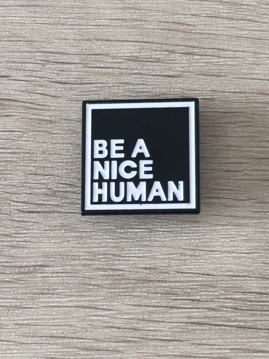 Pin carré noir et blanc « BE A NICE HUMAN » avec bordure argentée