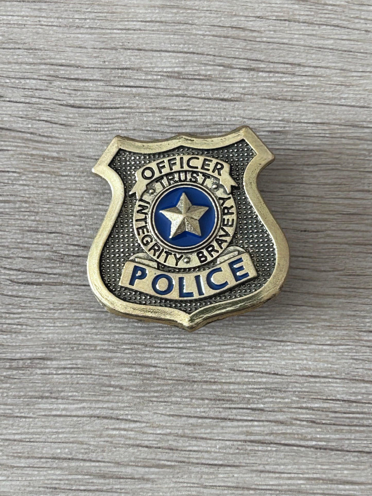 Badge de police américain en forme d’écusson doré, étoile bleue et texte « OFFICER POLICE »