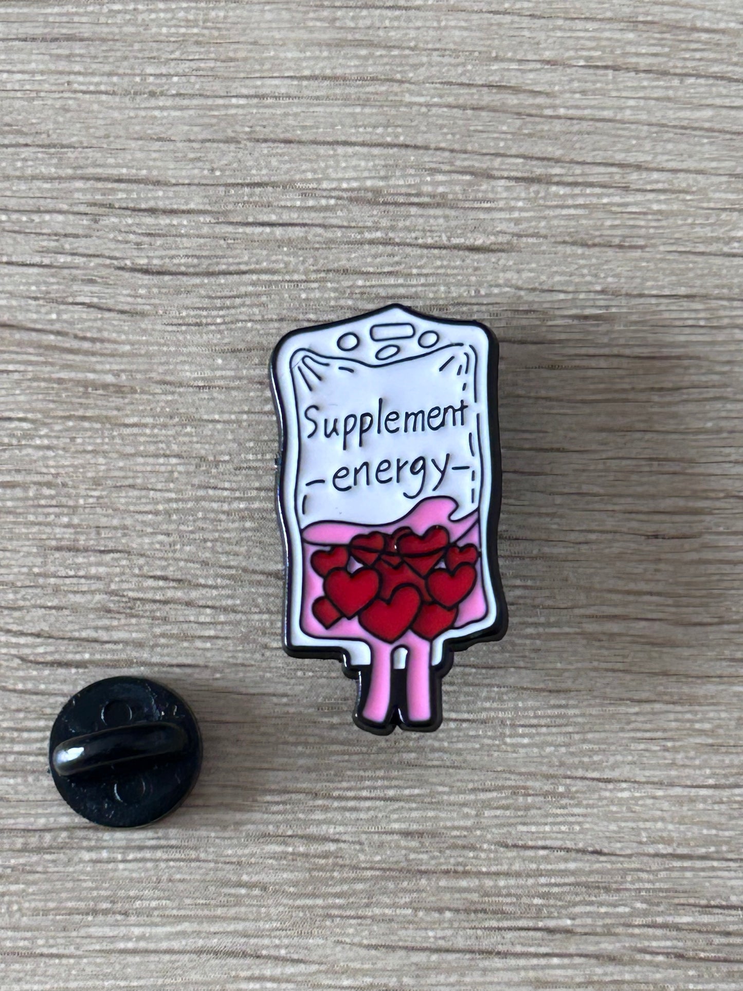 Broche de poche de perfusion en flacon bleu «Supplement energy», cœurs rouges, attache noire.