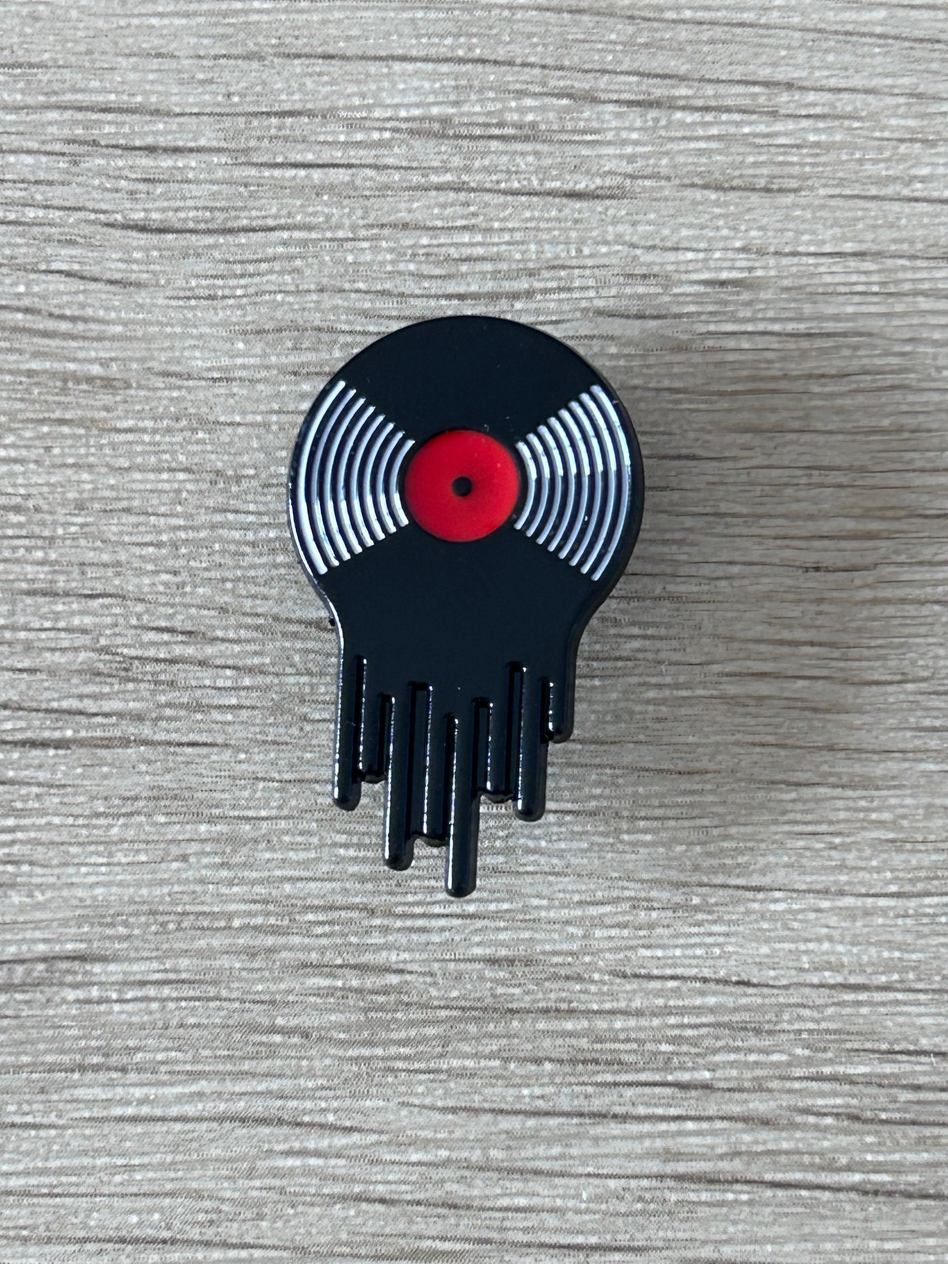 Broche vinyle qui semble  fondre, rayures argentées et centre rouge
