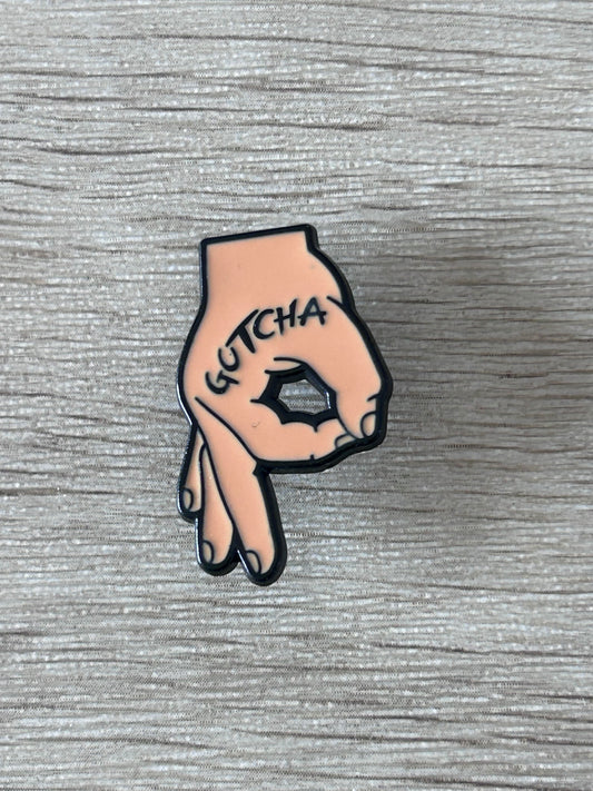 Épinglette en forme de main rose, « GOTCHA » sur le poing noir