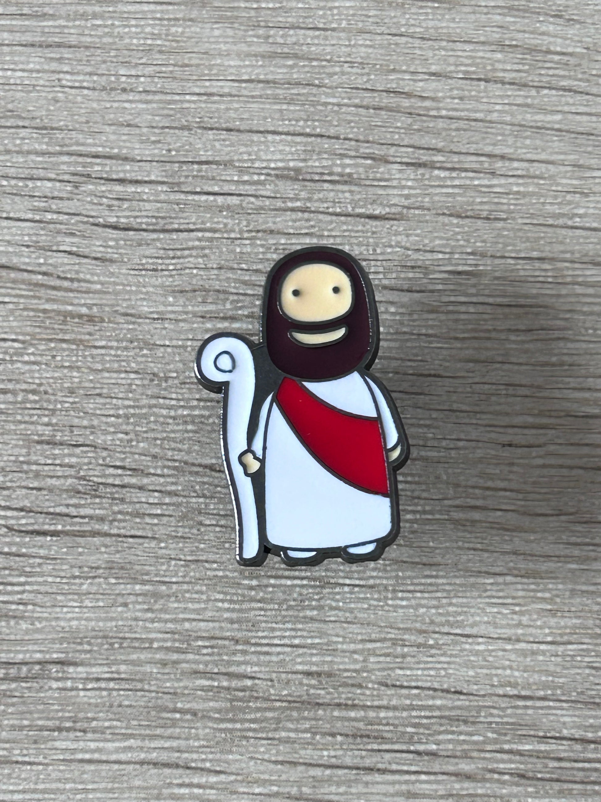Pin Jésus kawaii, robe blanche et cape rouge, main levée, auréole sombre
