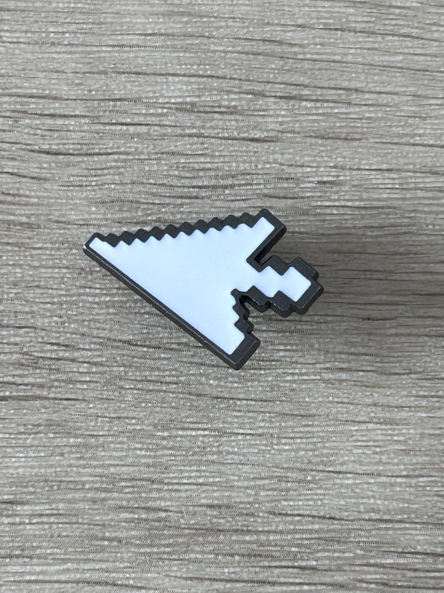 Épingle curseur pixel blanche bleutée avec bord et détails noirs, posée à plat.