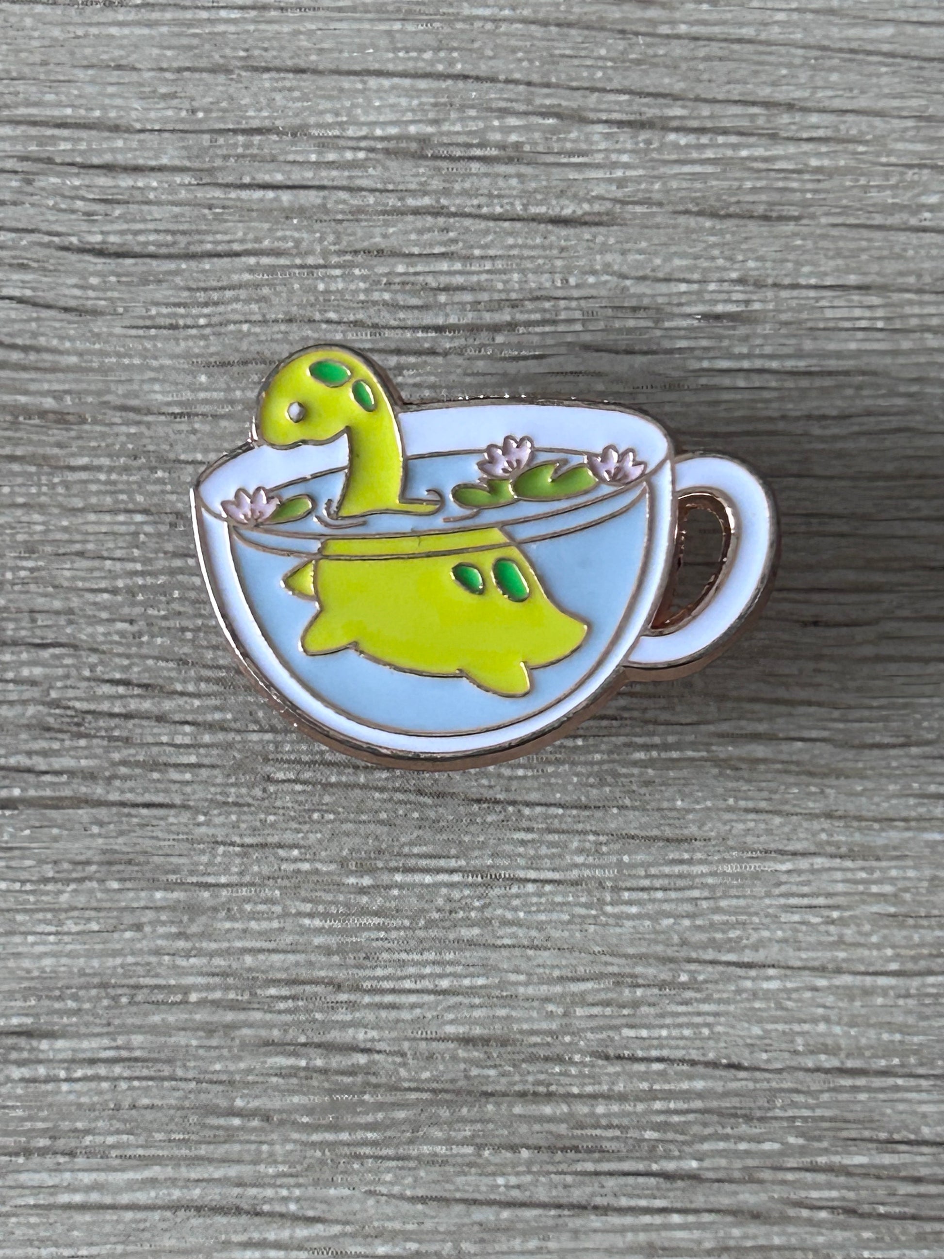 Épingle émail Nessie dans une tasse de thé bleu clair, corps vert, fleurs roses
