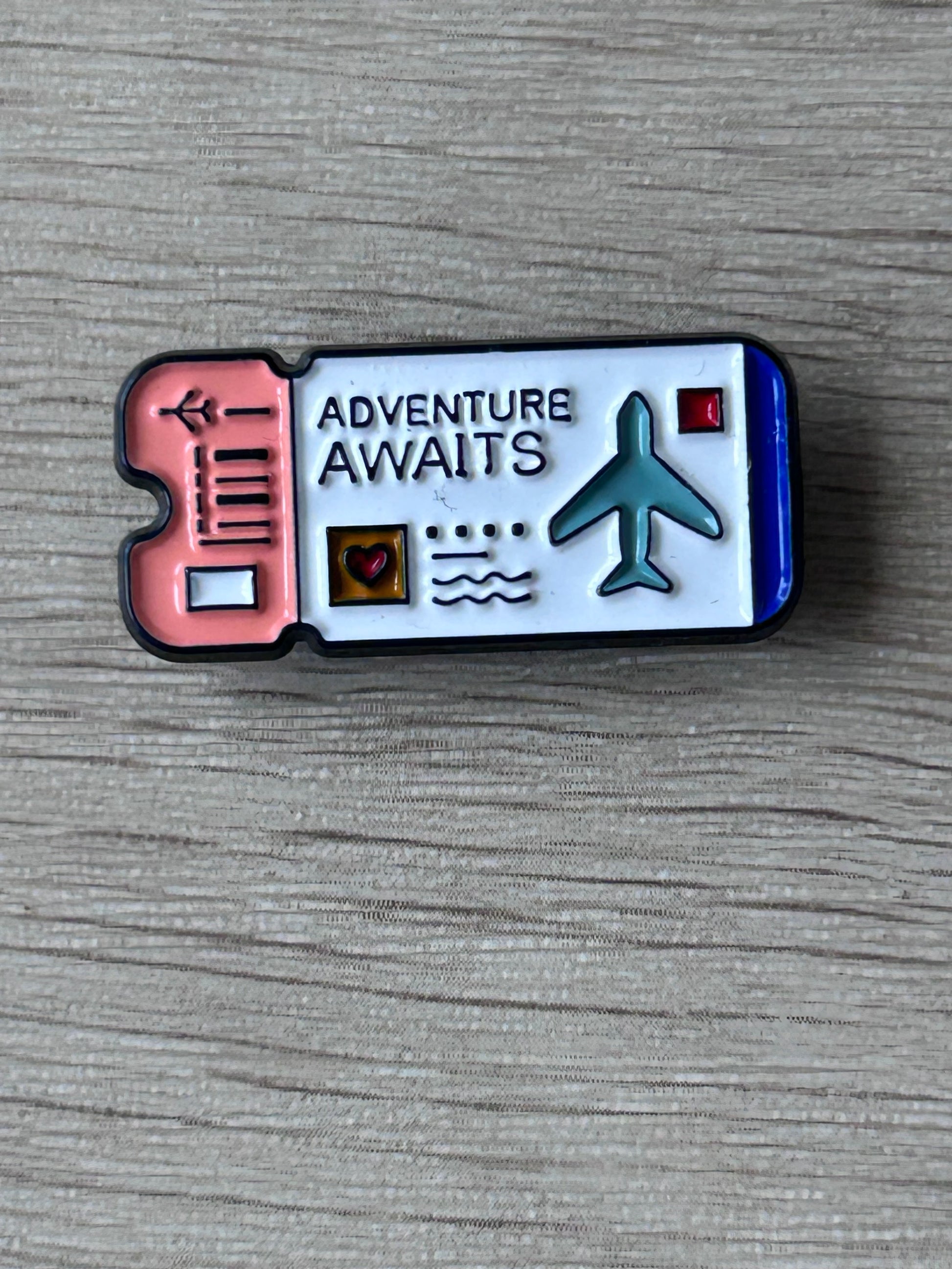 Gilet de voyage ? Non. Pin billet d’avion avec texte « Adventure Awaits » et icône avion