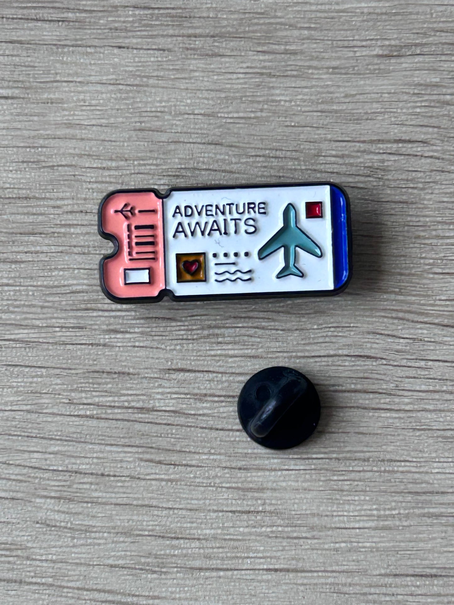 Pin billet d’avion « Adventure Awaits » avec icône avion, vue avec attache noire