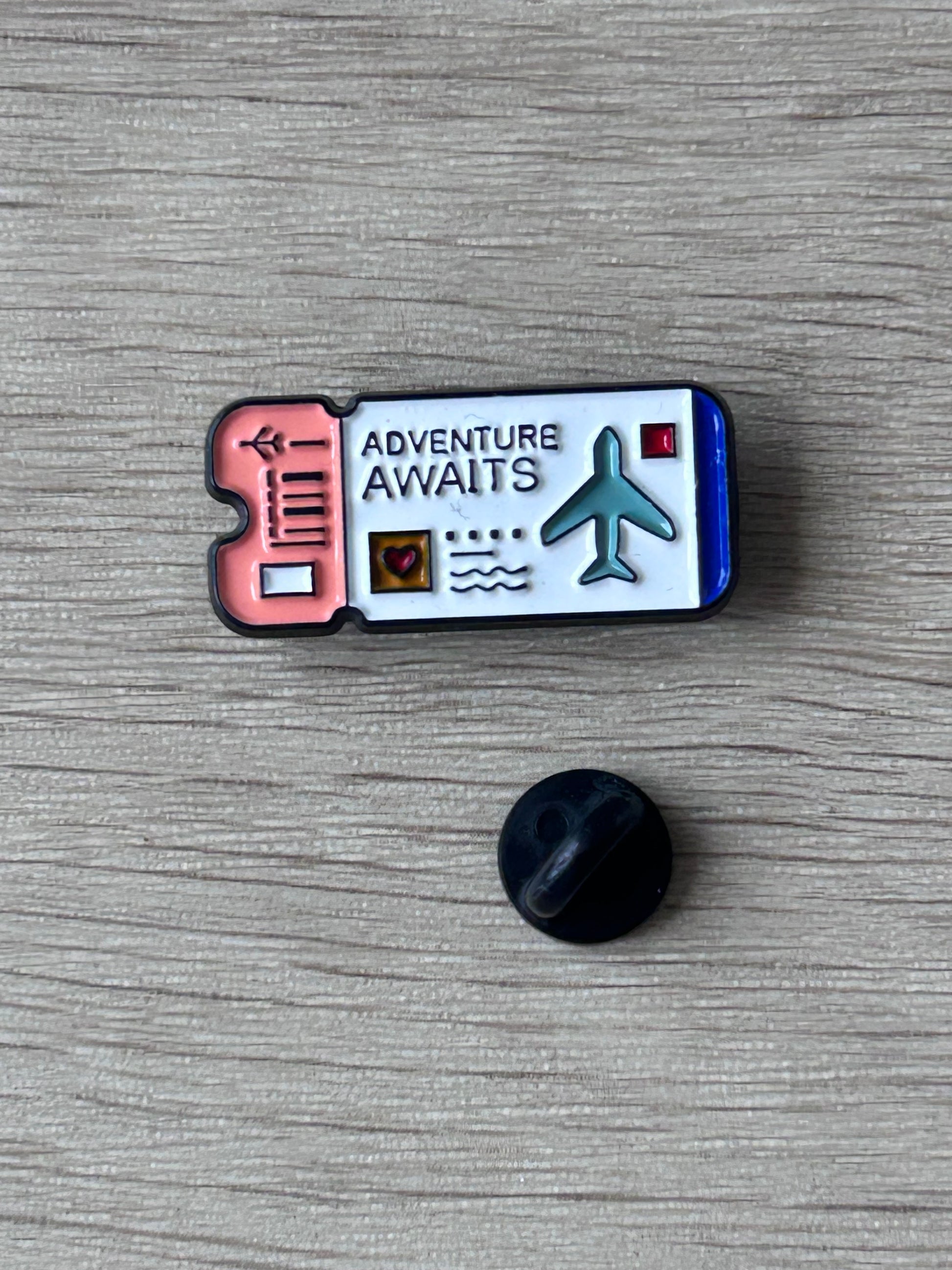 Pin billet d’avion « Adventure Awaits » avec icône avion, vue avec attache noire