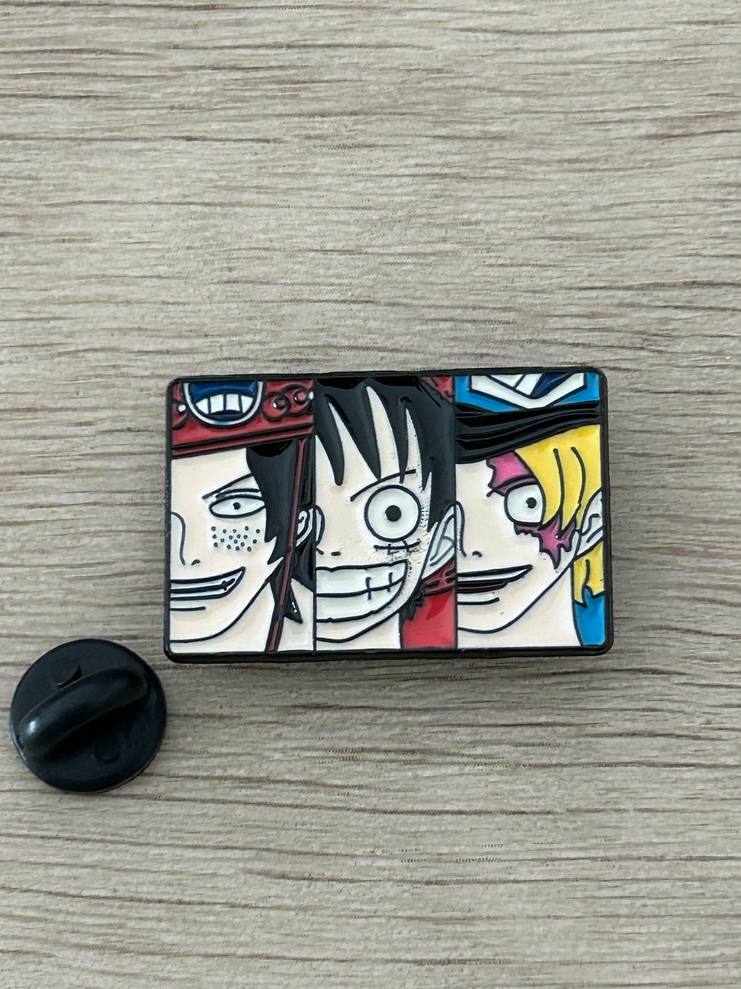 Épingle rectangulaire noire avec trois visages d’anime en couleurs vives
