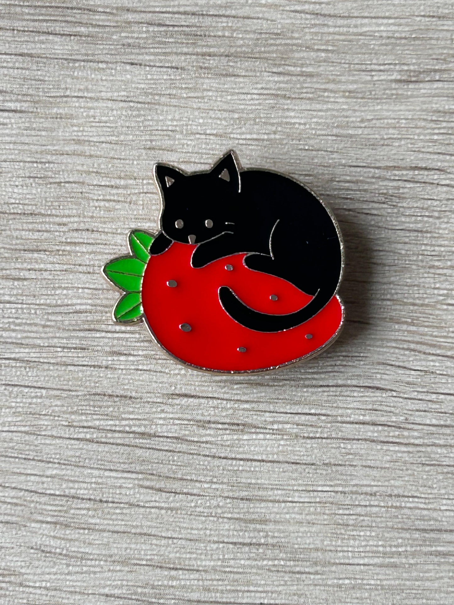Pin's chat noir sur une fraise
