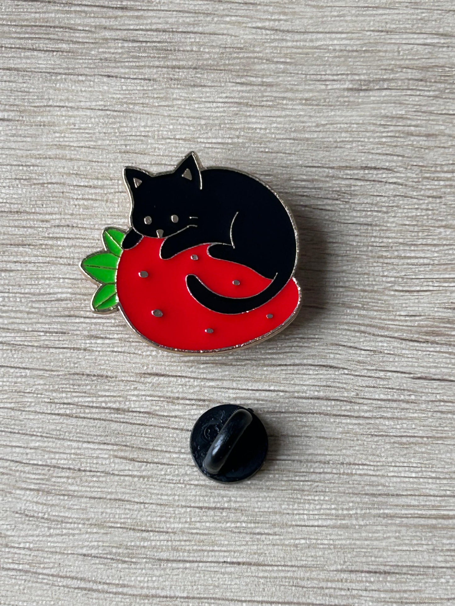 Pin's chat noir sur une fraise