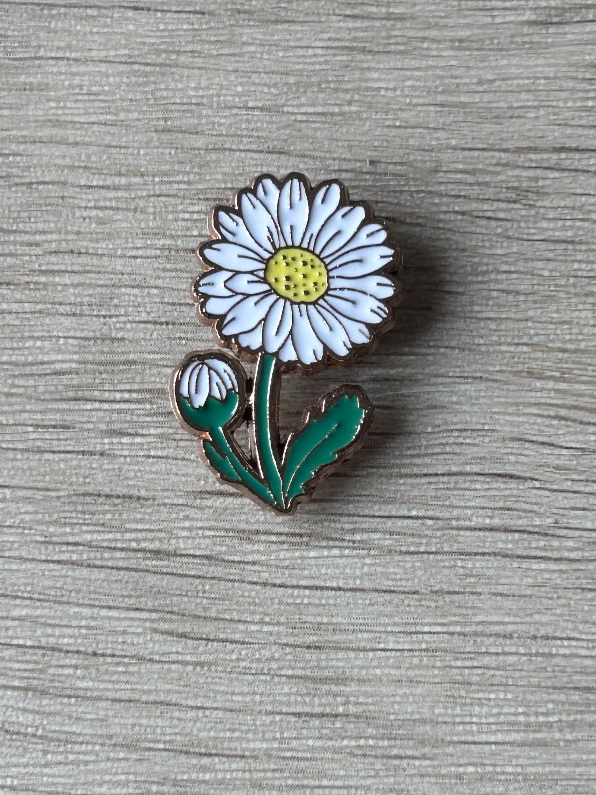 Pin's marguerite émaillé, fleur blanche à cœur jaune, tige et feuilles vertes.