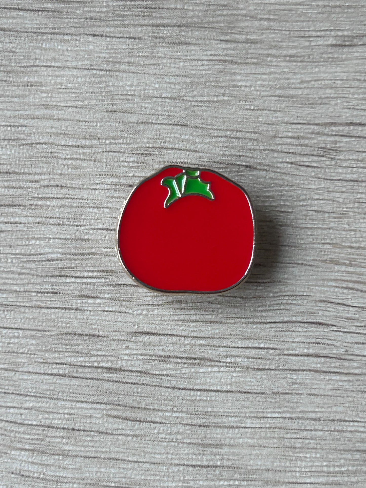 Pin's tomate rouge émaillé avec feuilles vertes et bord argenté