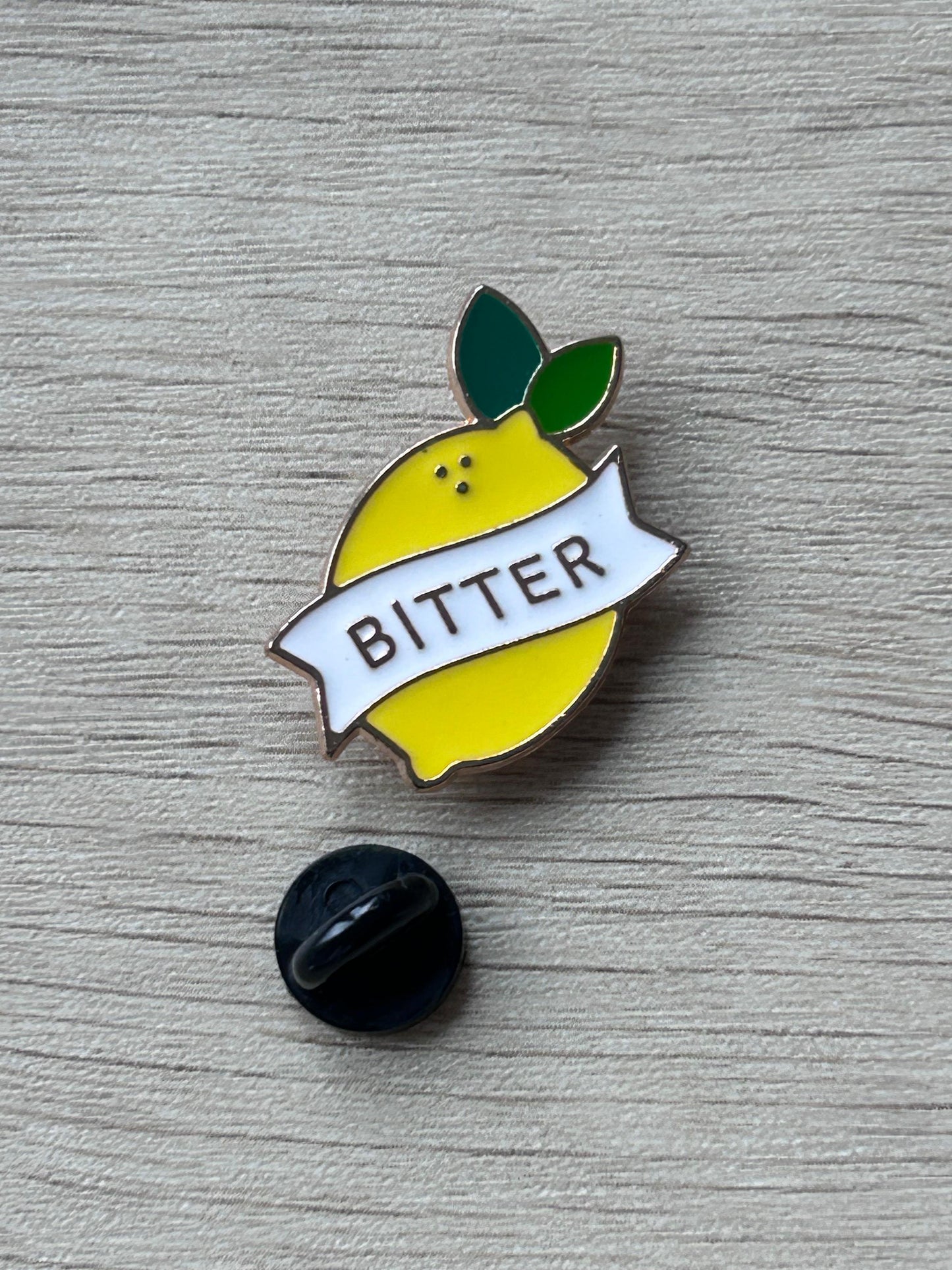 Épingle citron jaune « BITTER » avec feuilles vertes, accompagnée d’un fermoir