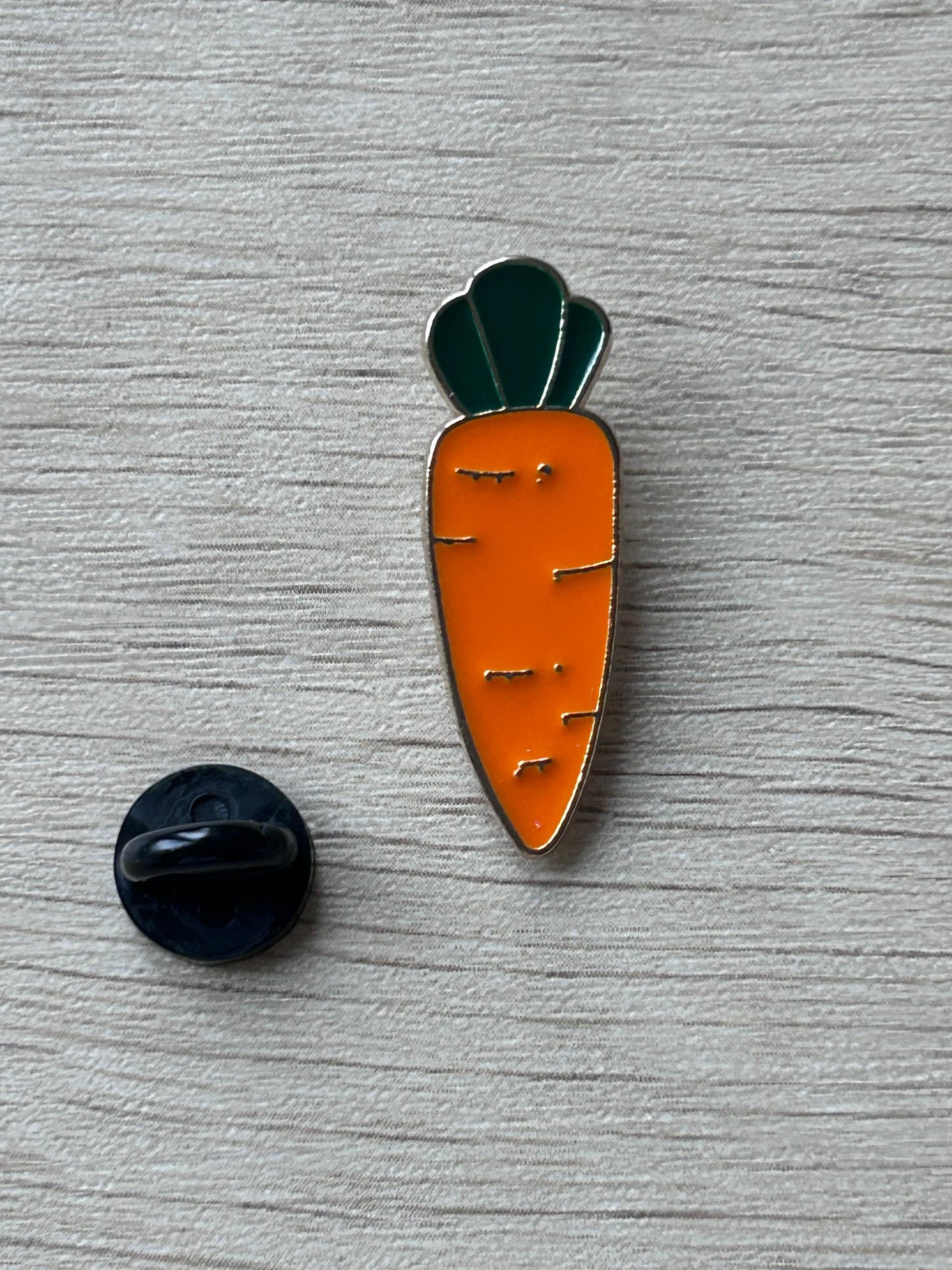 Broche en forme de carotte orange avec tige vert foncé, vue avec attache.