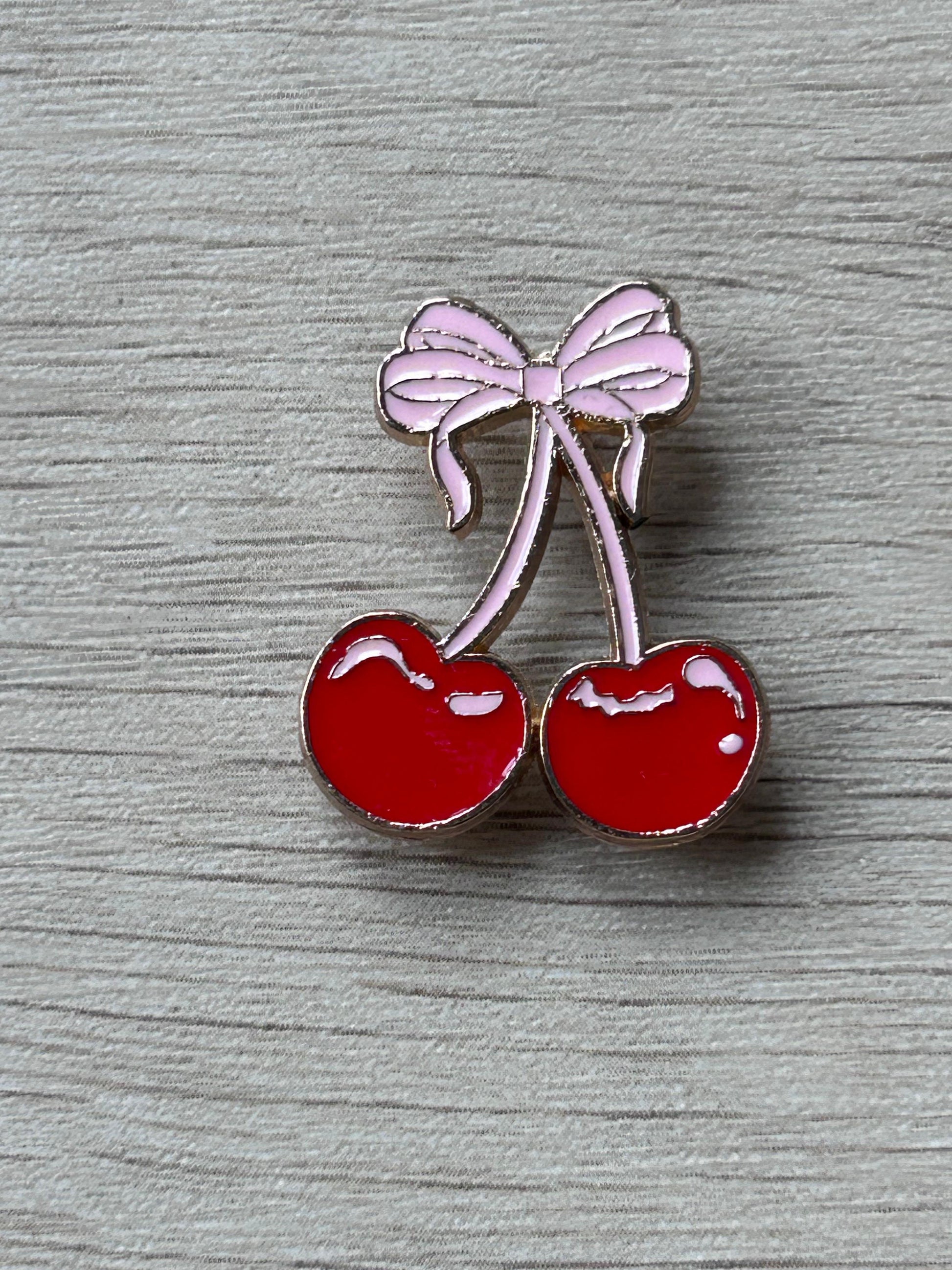 Pin en émail de deux cerises rouges avec nœud rose
