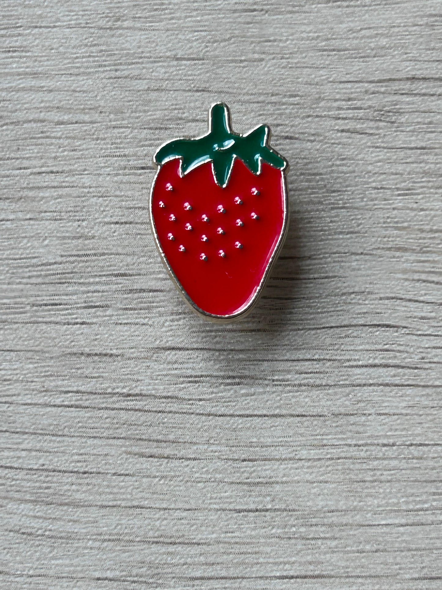 Pin fraise émaillée rouge avec feuillage vert et motifs blancs