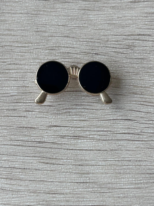 Broche lunettes rondes noires : monture argentée et embouts gris, verres noirs.