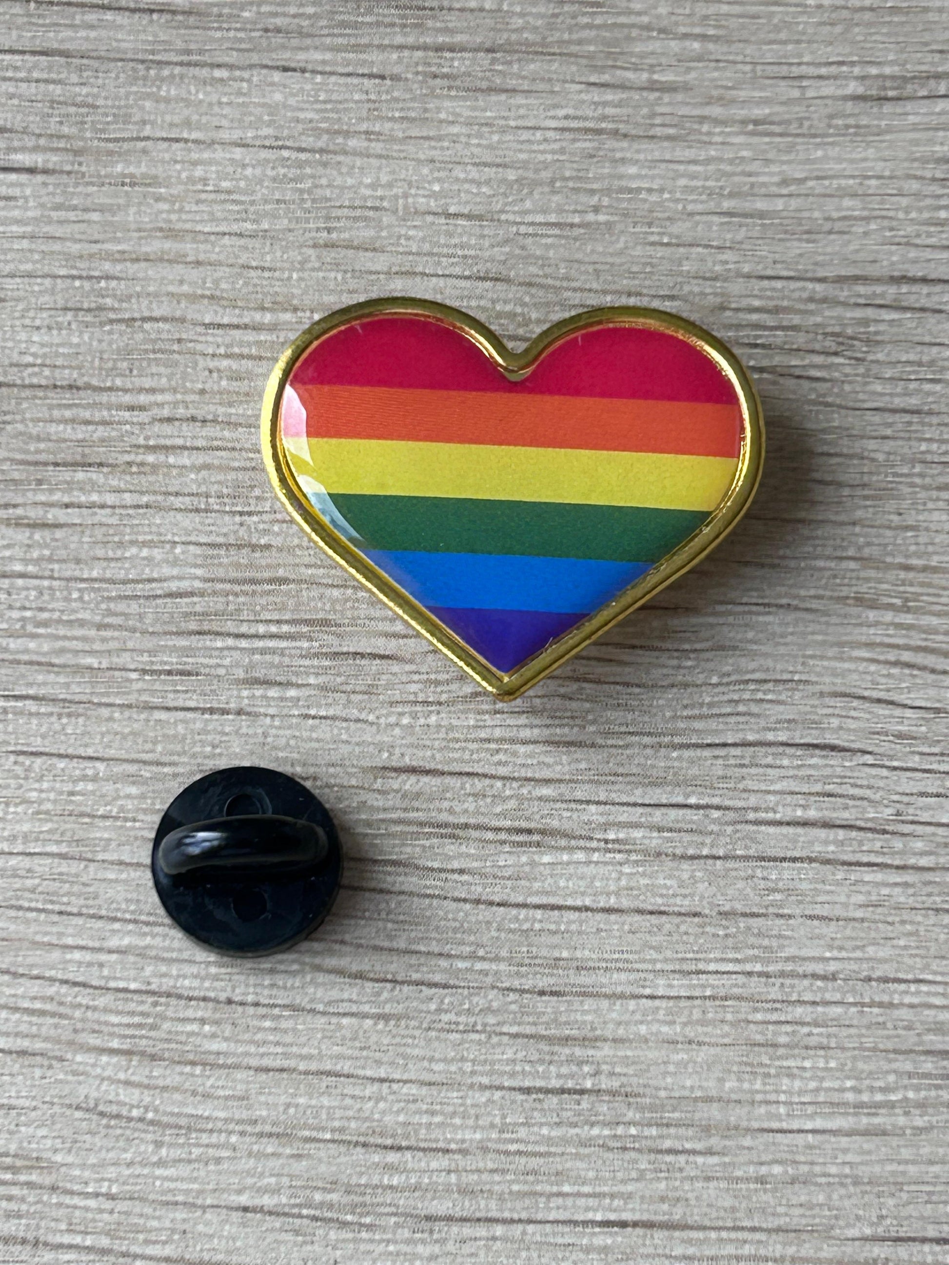 Pin cœur arc-en-ciel à contour doré.